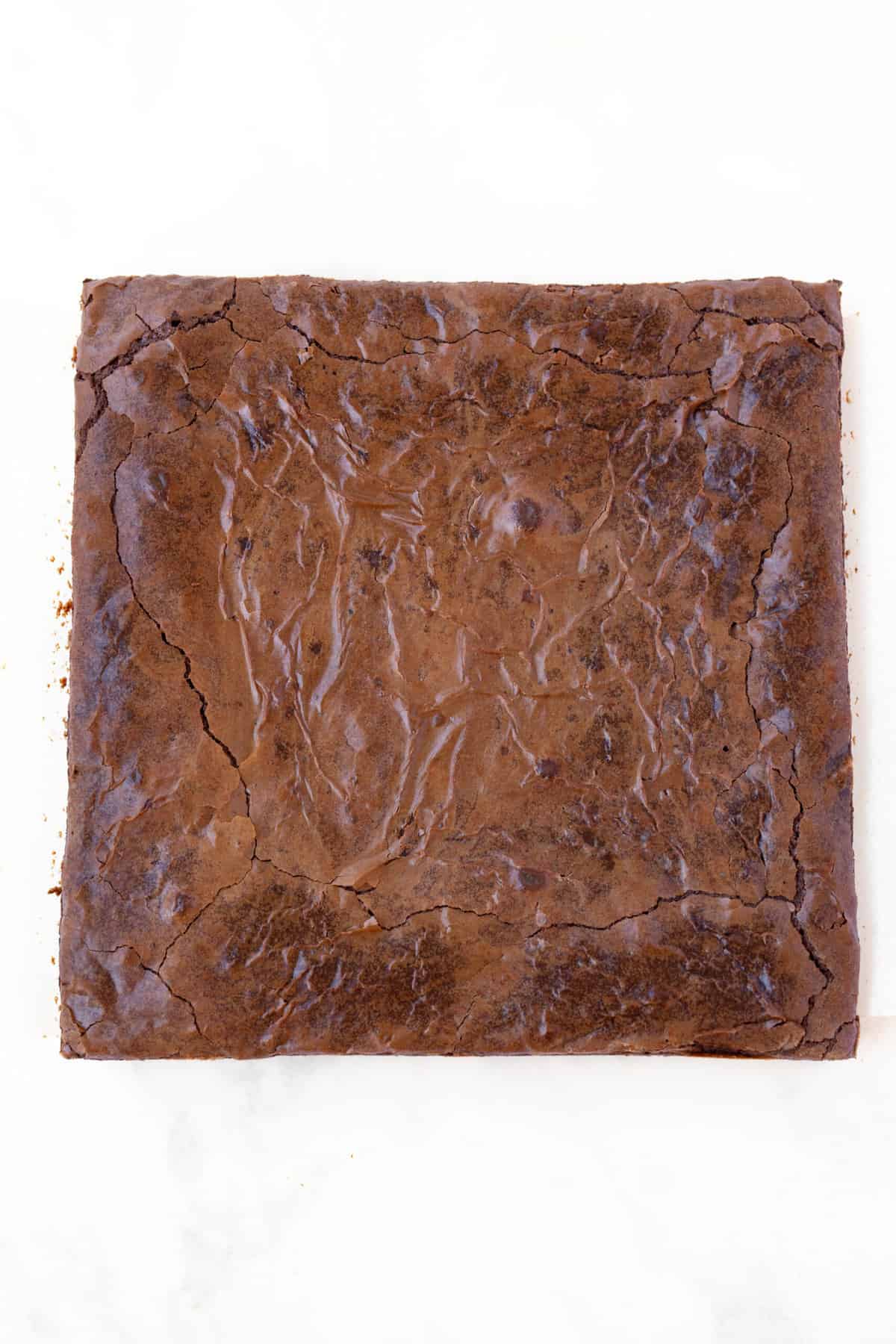 Top view of a homemade Shiny Top Brownie on a white background.