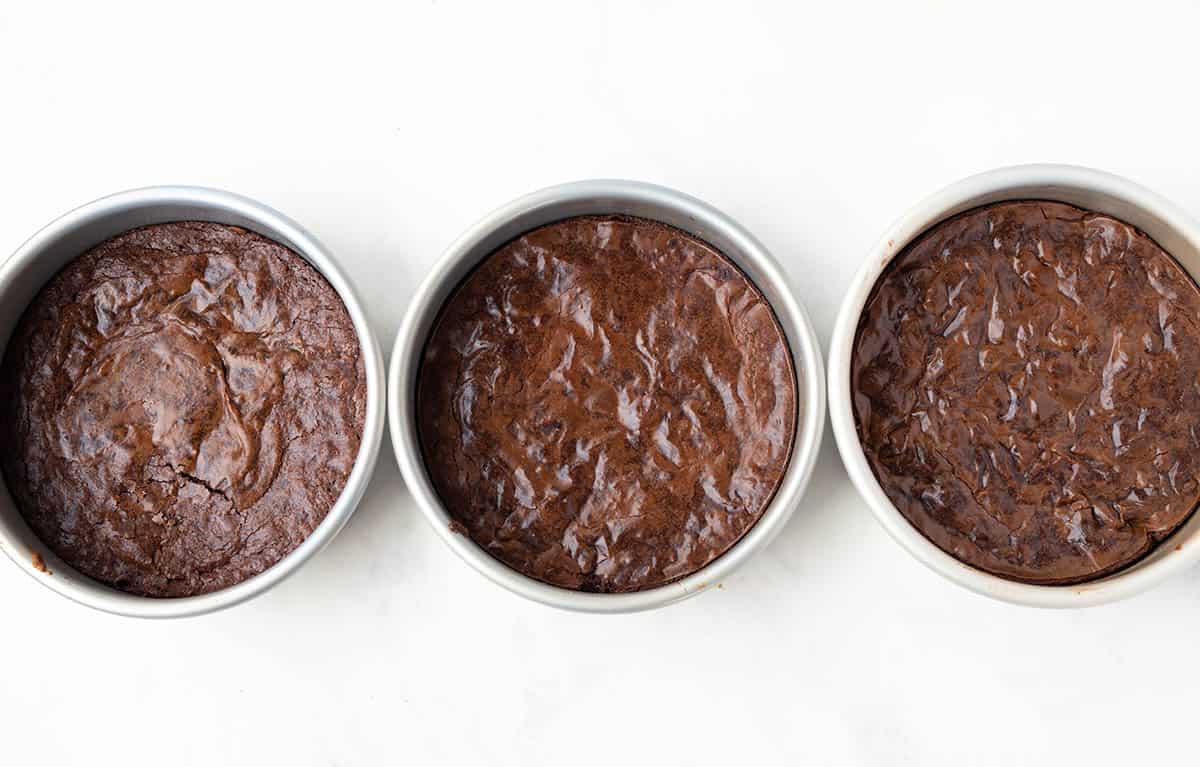 Three different brownies all sitting in cake pans fresh from the oven.