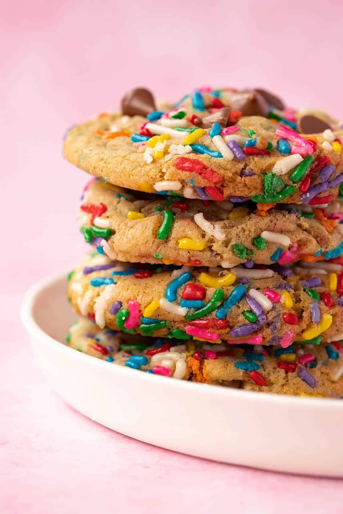 A stack of homemade Funfetti Chocolate Chip Cookies on a white plate. 