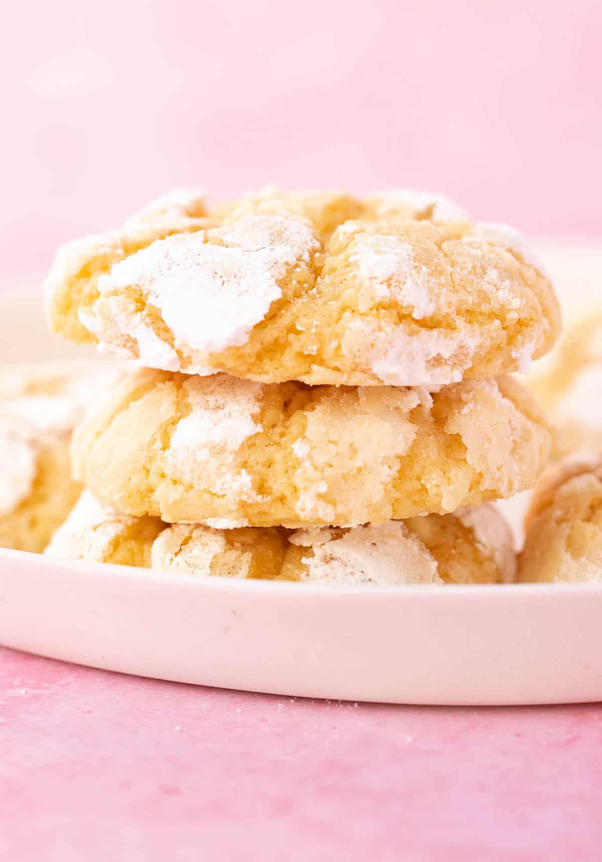 A stack of Lemon Crinkle Cookies on a pink background.