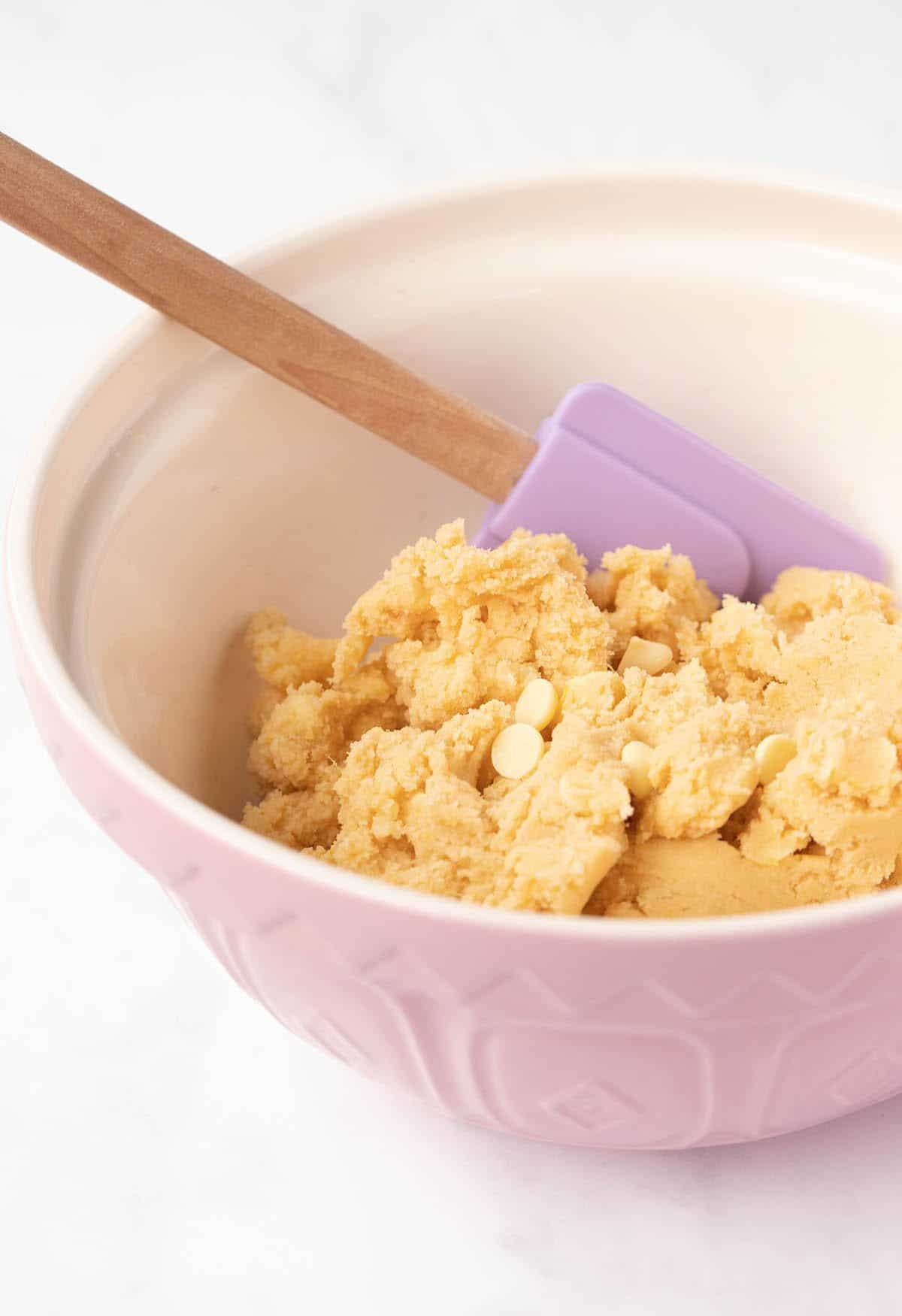 A mixing bowl with cookie dough in it.