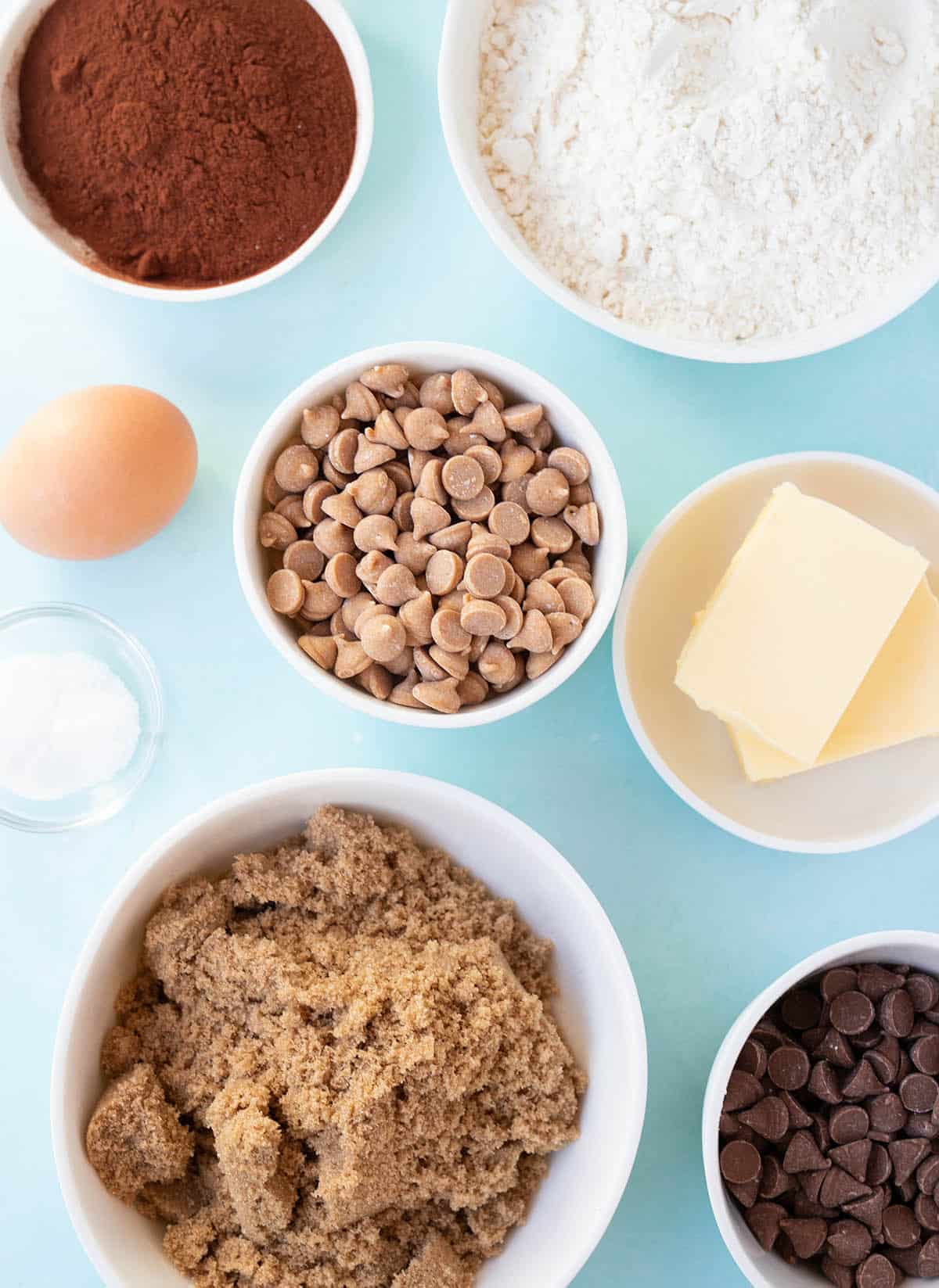 All the ingredients needed to make chocolate peanut butter chip cookies on a blue background. 