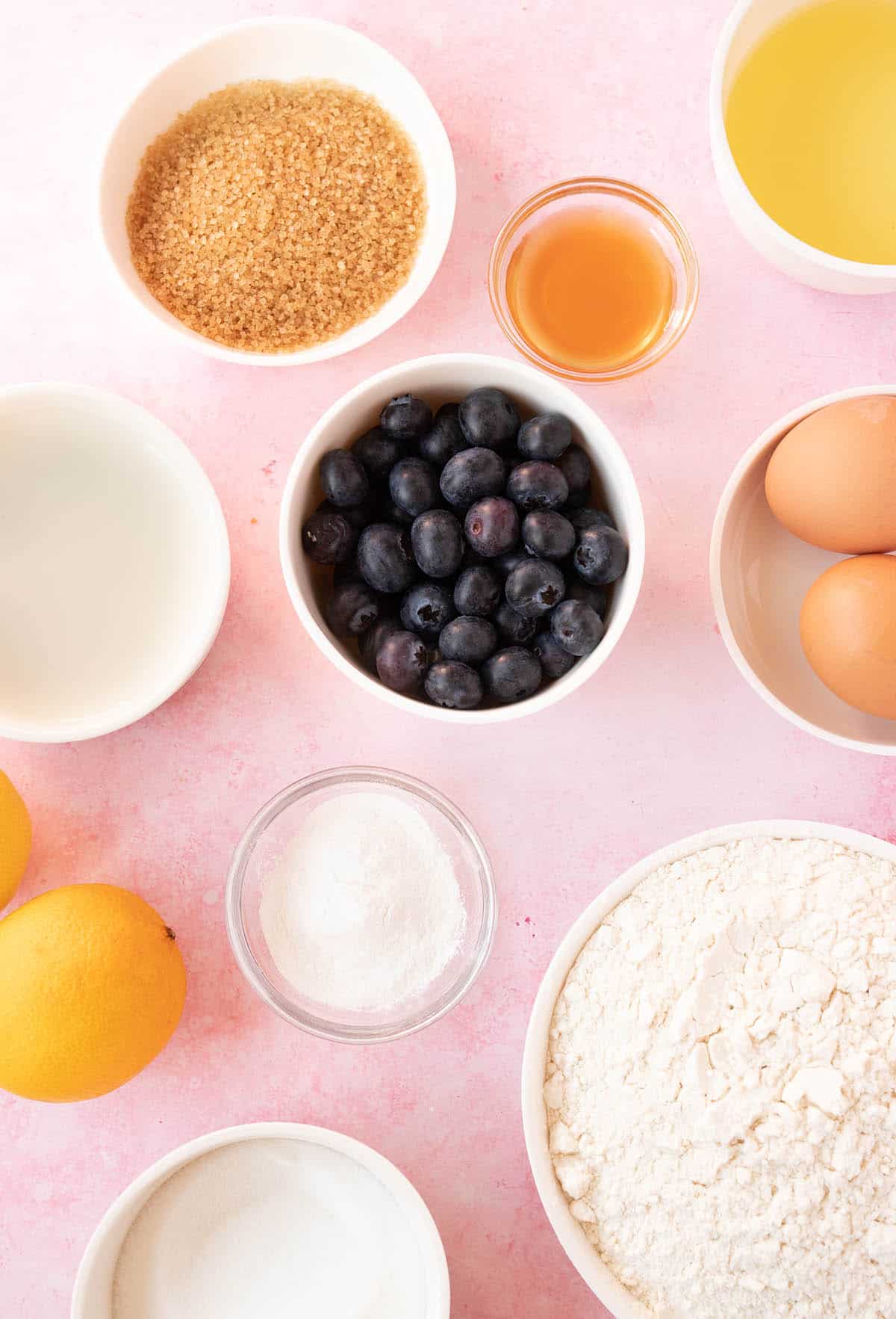 All the ingredients needed for muffins on a pink background.