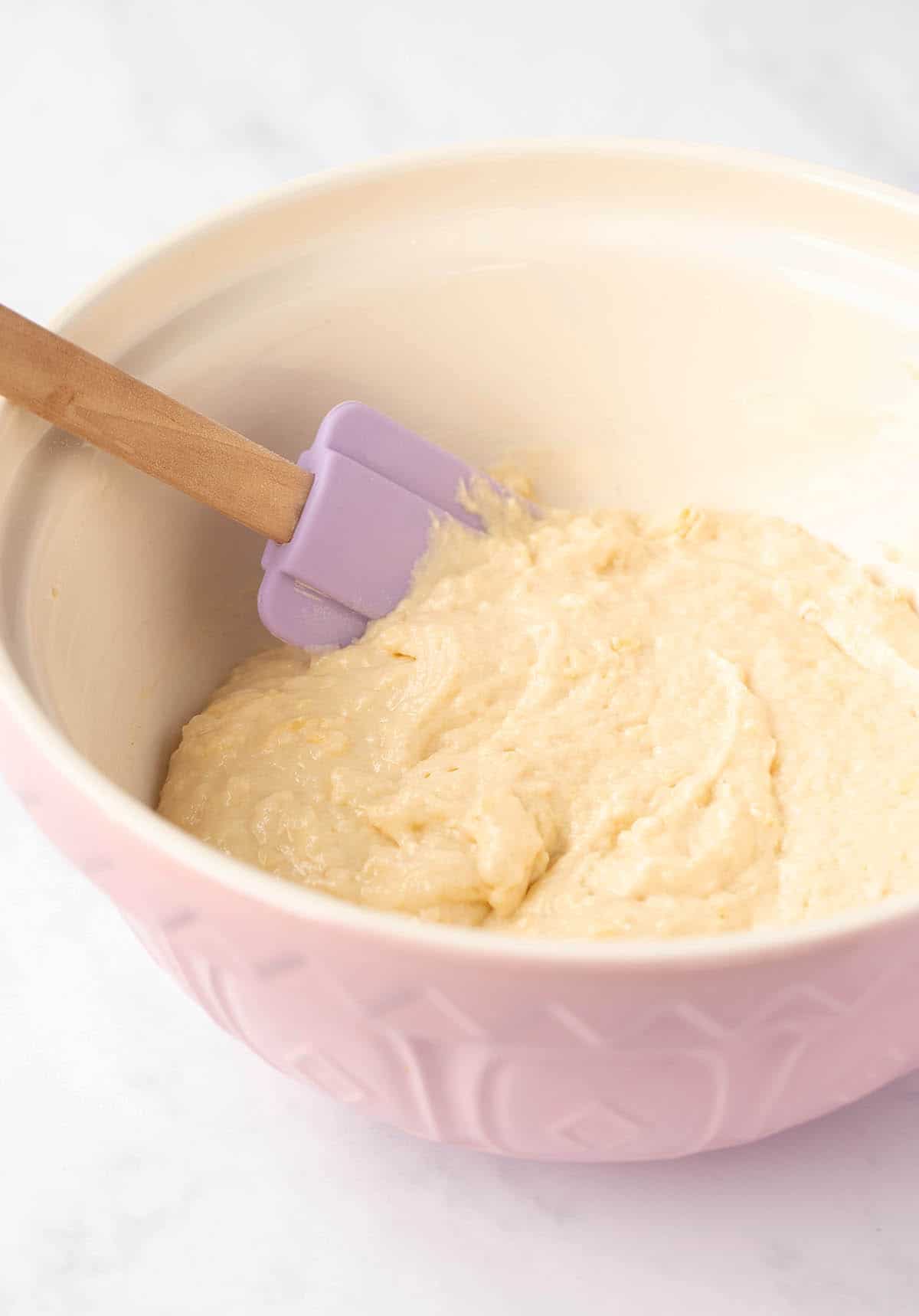 A pink mixing bowl filled with pancake batter.
