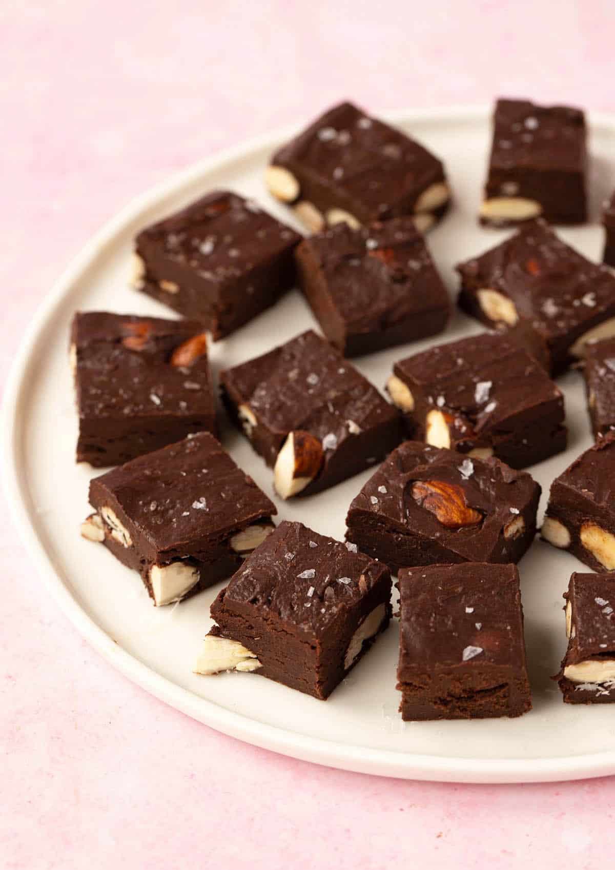 A white plate filled with pieces of Chocolate Almond Fudge on it, ready for serving.