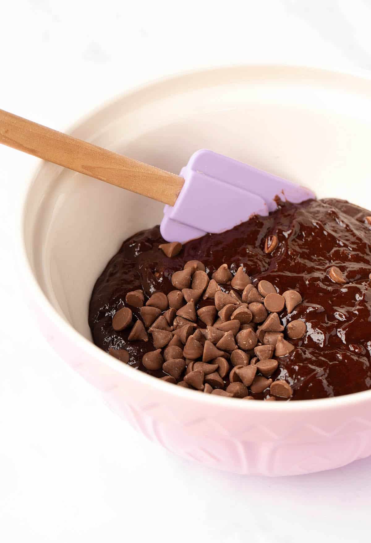 A pink mixing bowl filled with chocolate brownie batter.