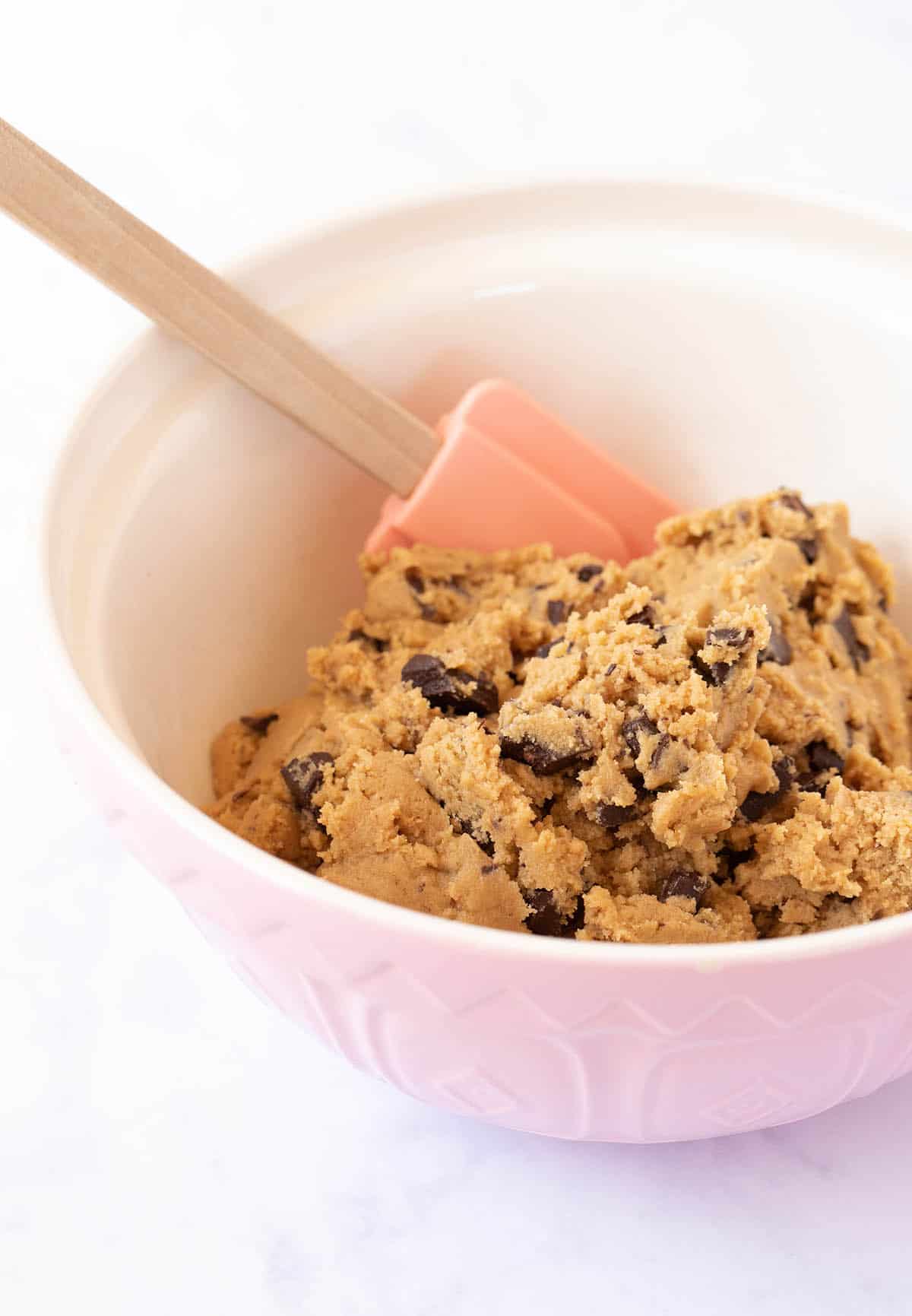 A pink bowl filled with peanut butter cookie dough.