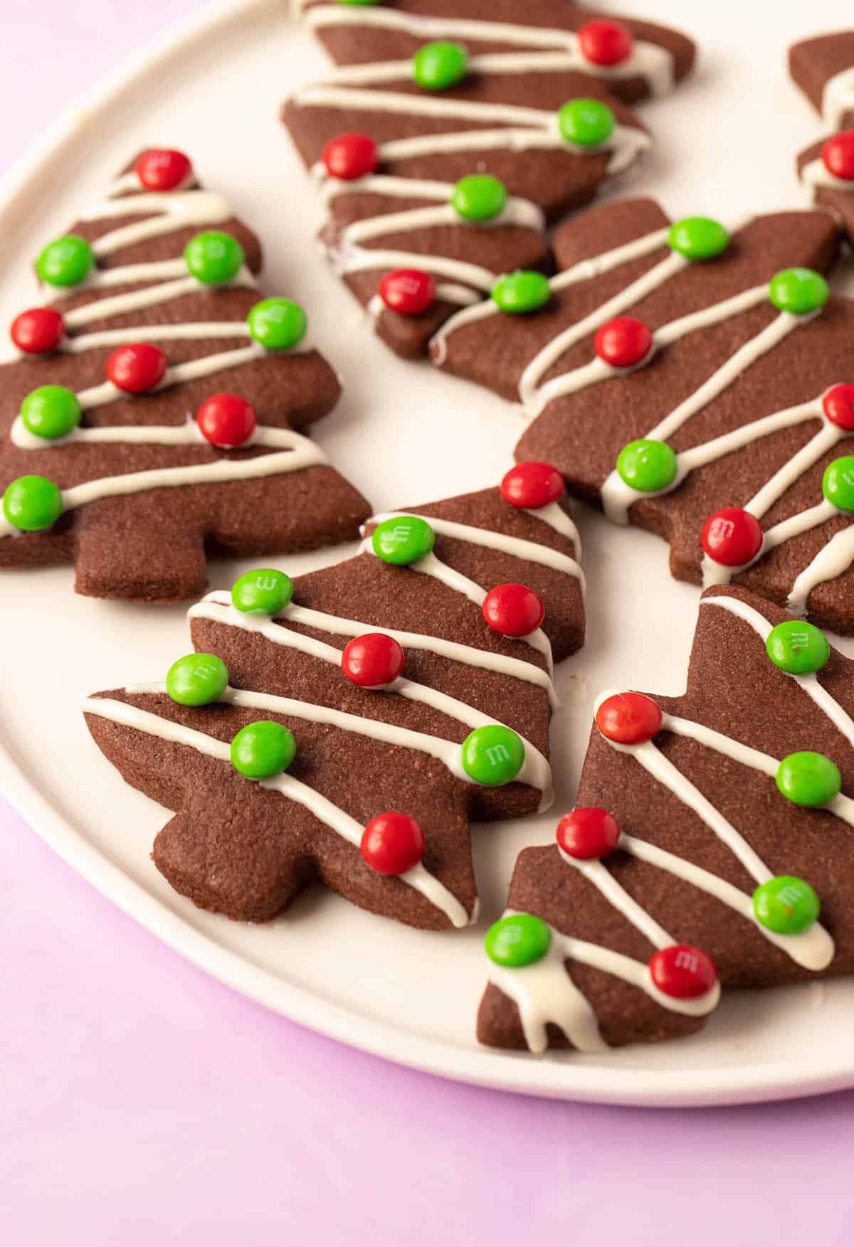 A plate of chocolate Christmas tree cookies decorated with mini M&M’s. 