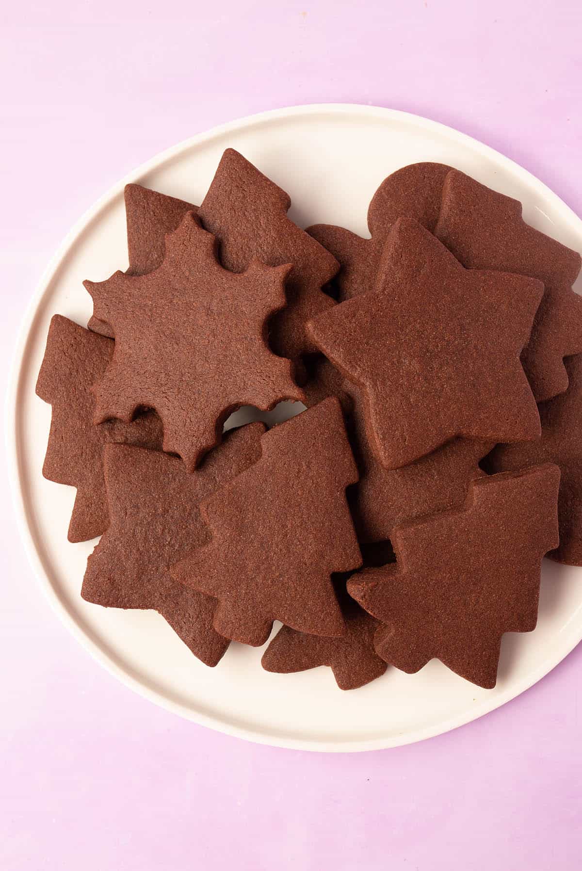 Top view of a white plate filled with chocolate cut-out cookies.