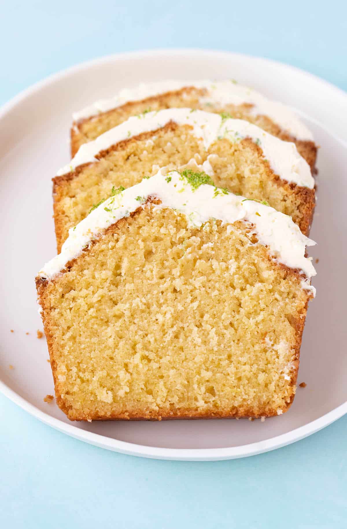 Slices of coconut cake with cream cheese frosting on a white plate