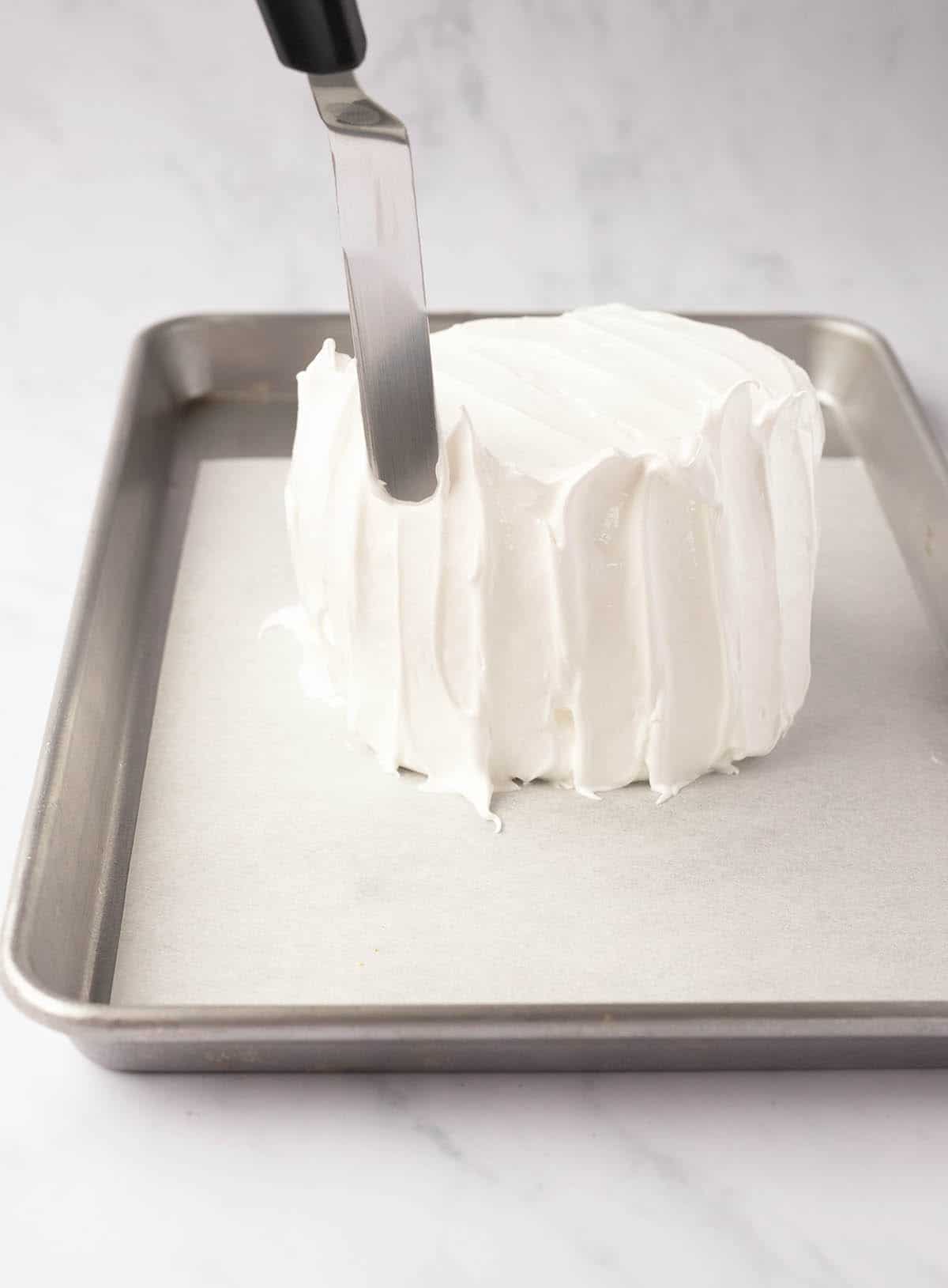 A hand showing how to craft meringue for a tall pavlova.