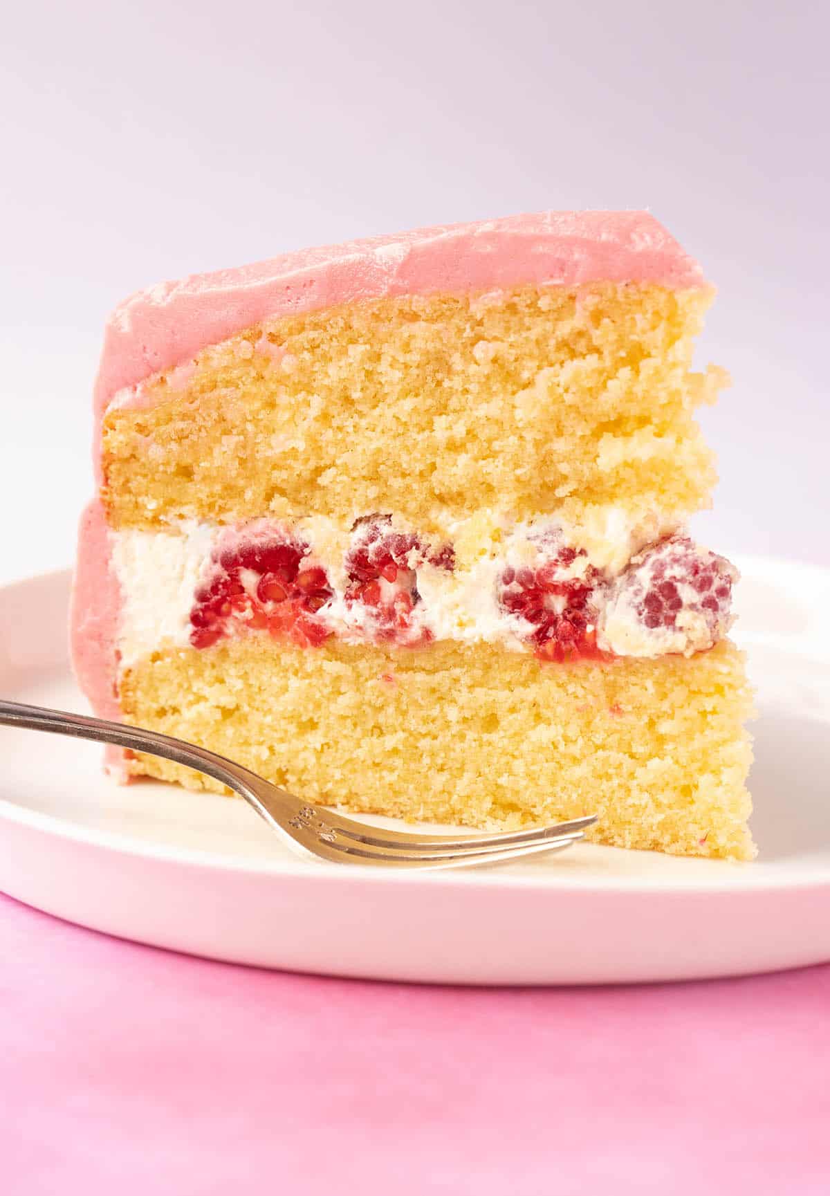 A generous slice of Lemon Raspberry Cake filled with whipped cream. 