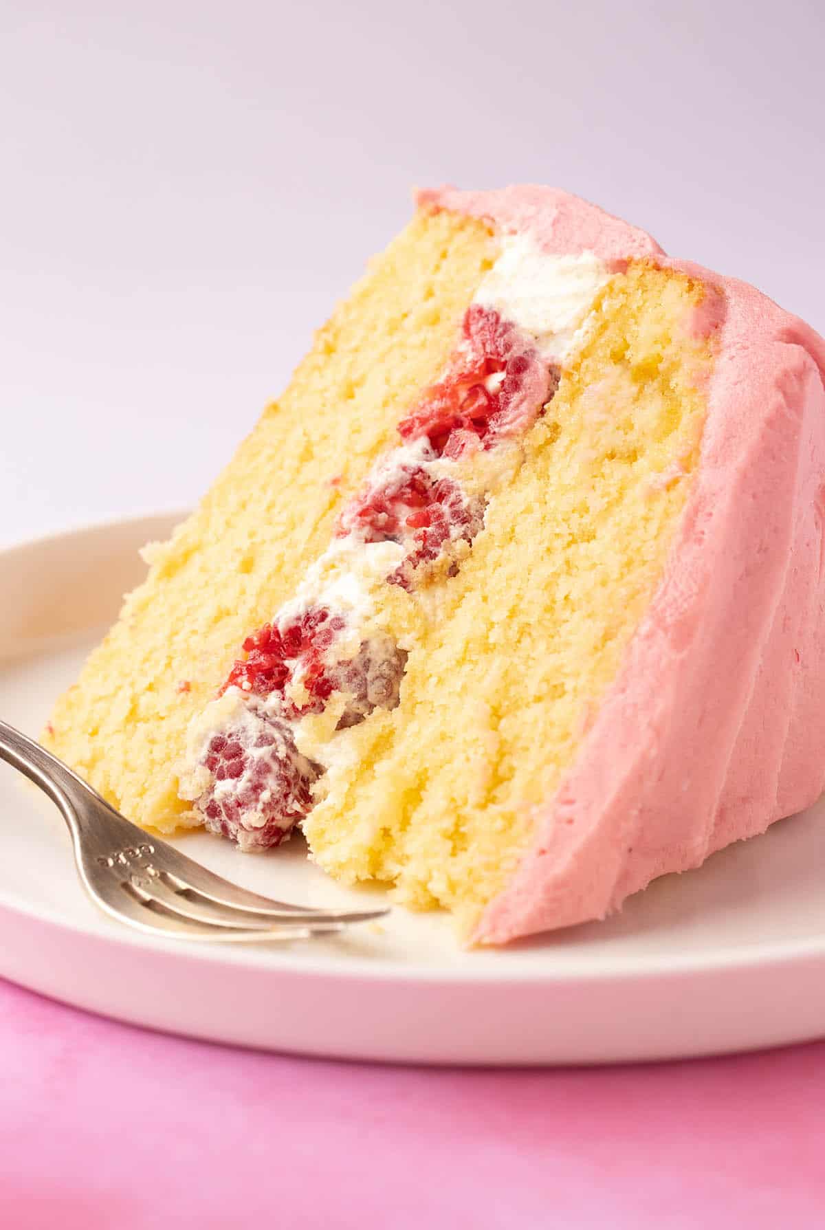 A big slice of Lemon Raspberry Cake on a white plate. 