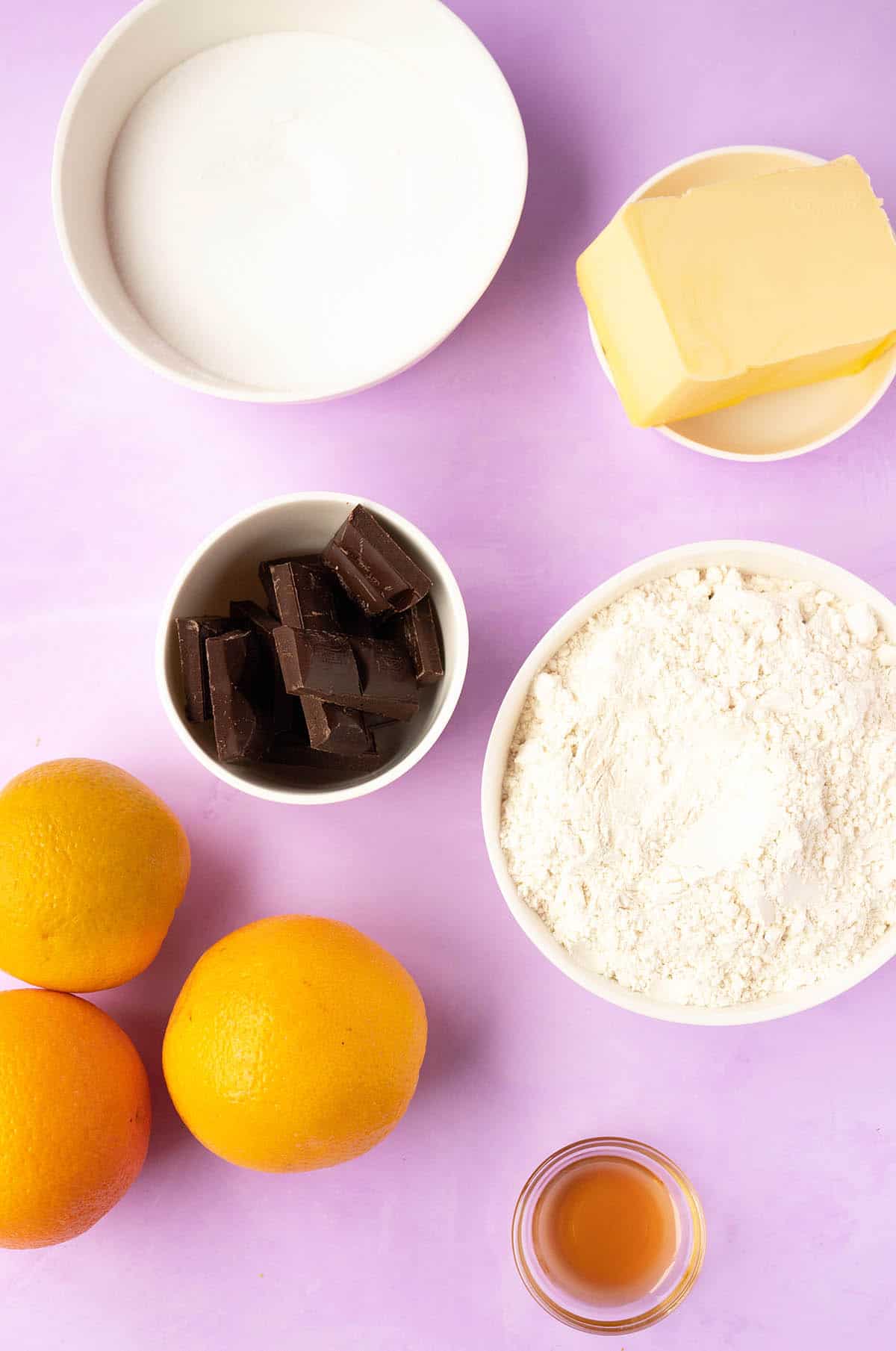 All the ingredients needed to make Orange Cookies from scratch on a purple background.