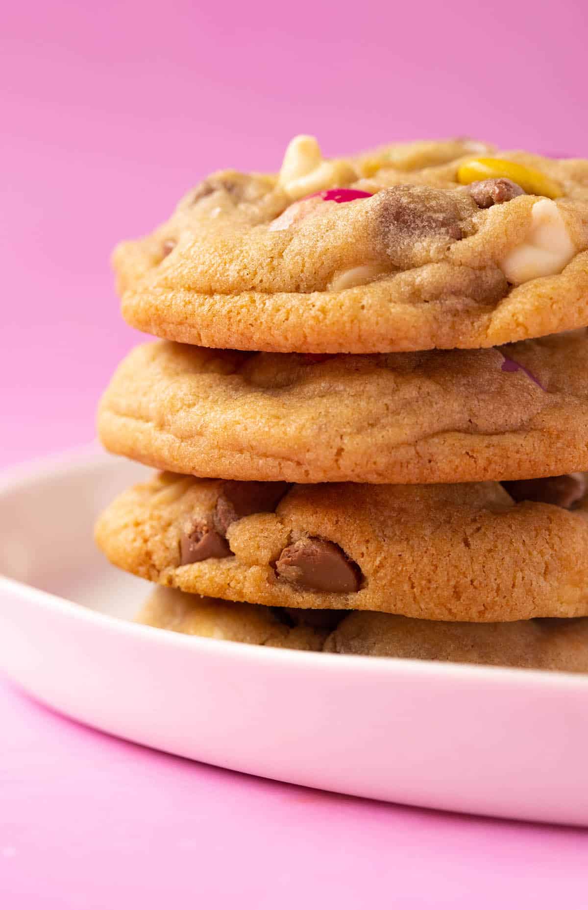 A tall stack of Smartie Cookies on a white plate. 