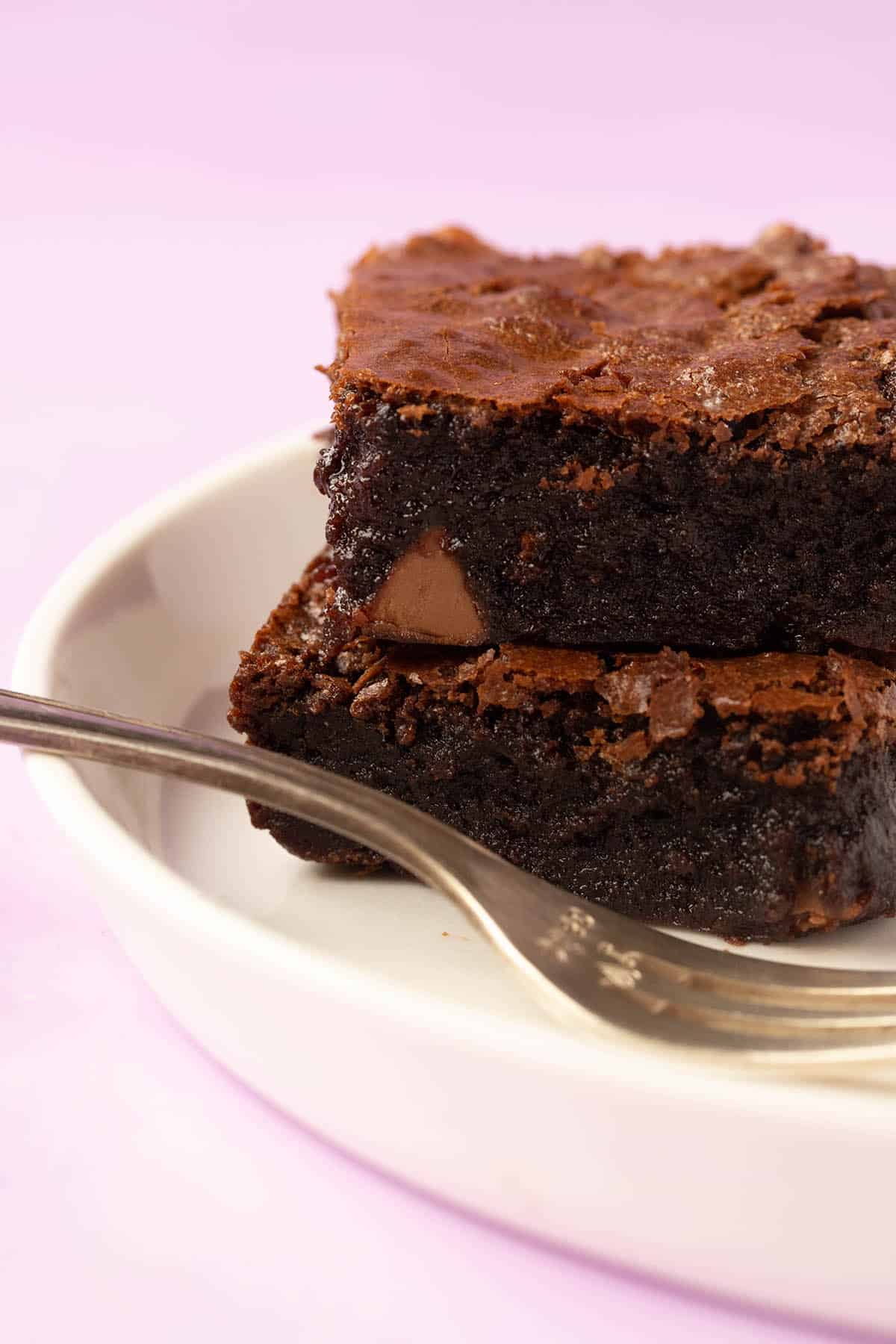 Two fudgy gluten free brownies sitting on a white plate. 