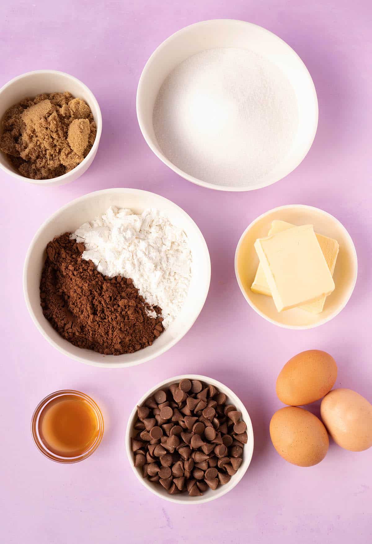 All the ingredients needed to make gluten free brownies from scratch on a purple background.