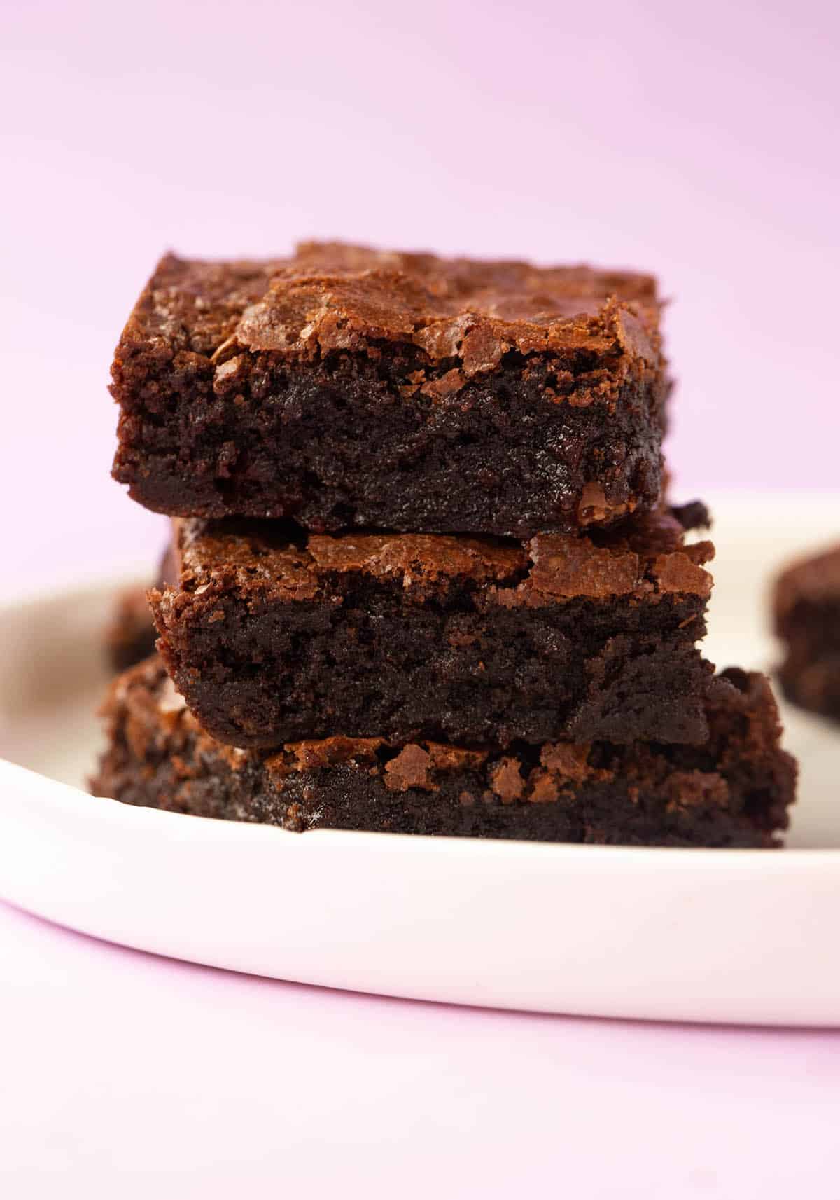 A stack of gluten free brownies on a purple backdrop.