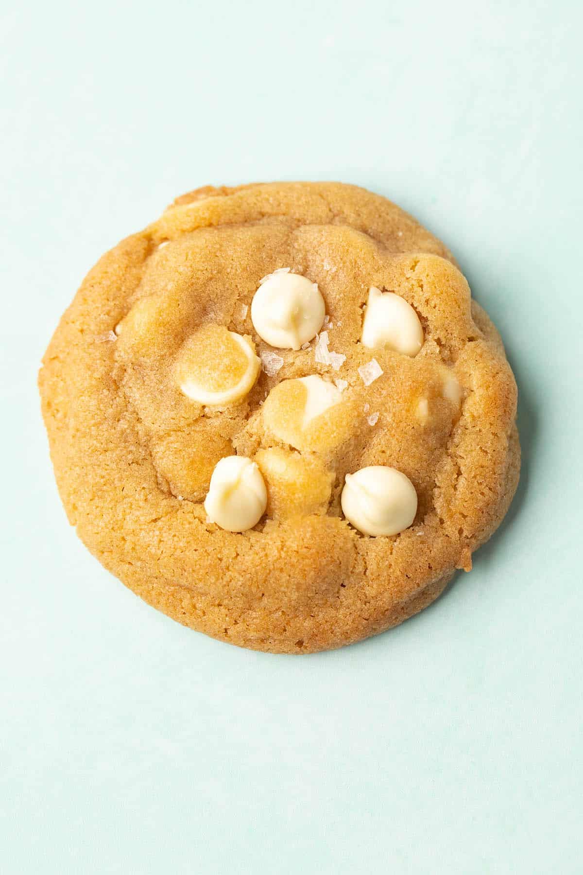 Top view of a cookie topped with white chocolate chips and sea salt. 