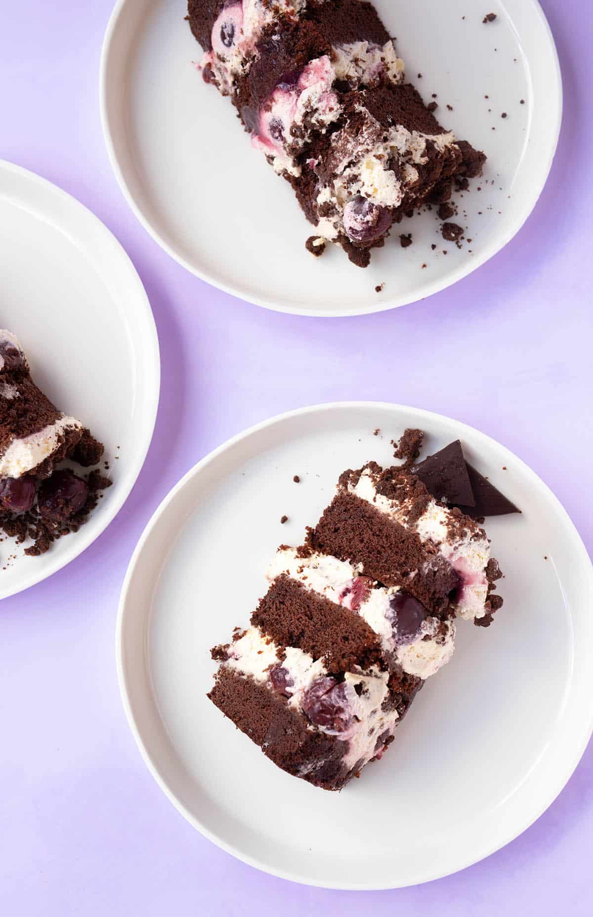 Top view of a sliced Black Forest Cake on a purple backdrop. 