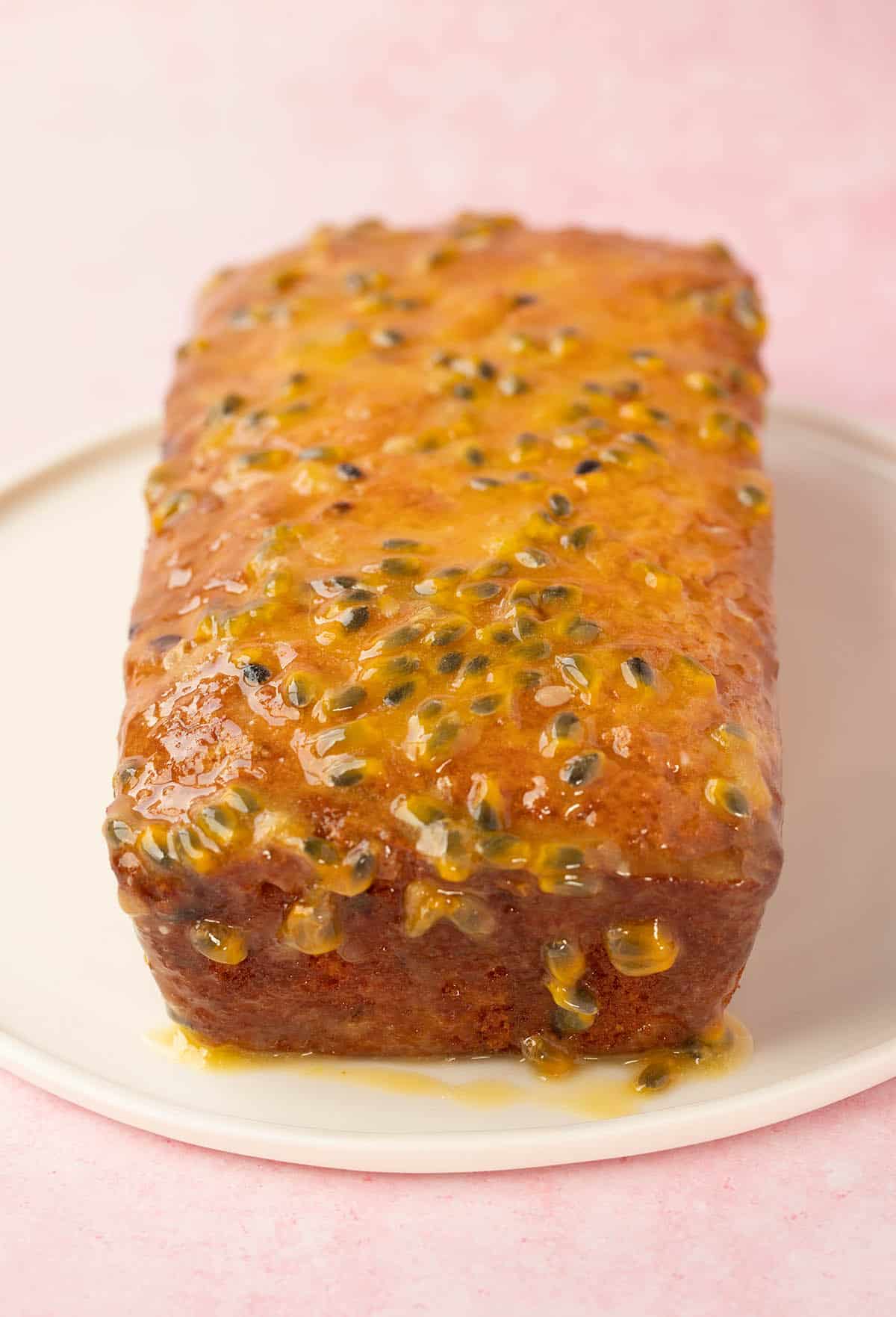 A Passionfruit Loaf Cake on a pink background.