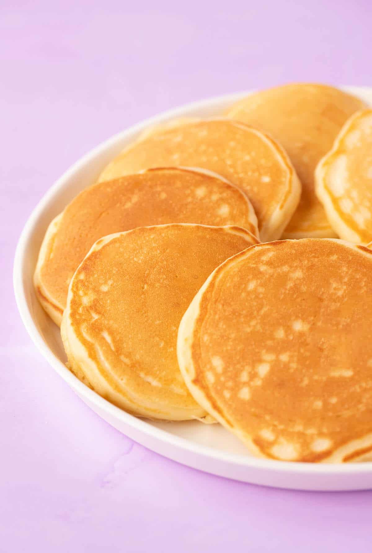 A plate of mini pancakes on a purple backdrop