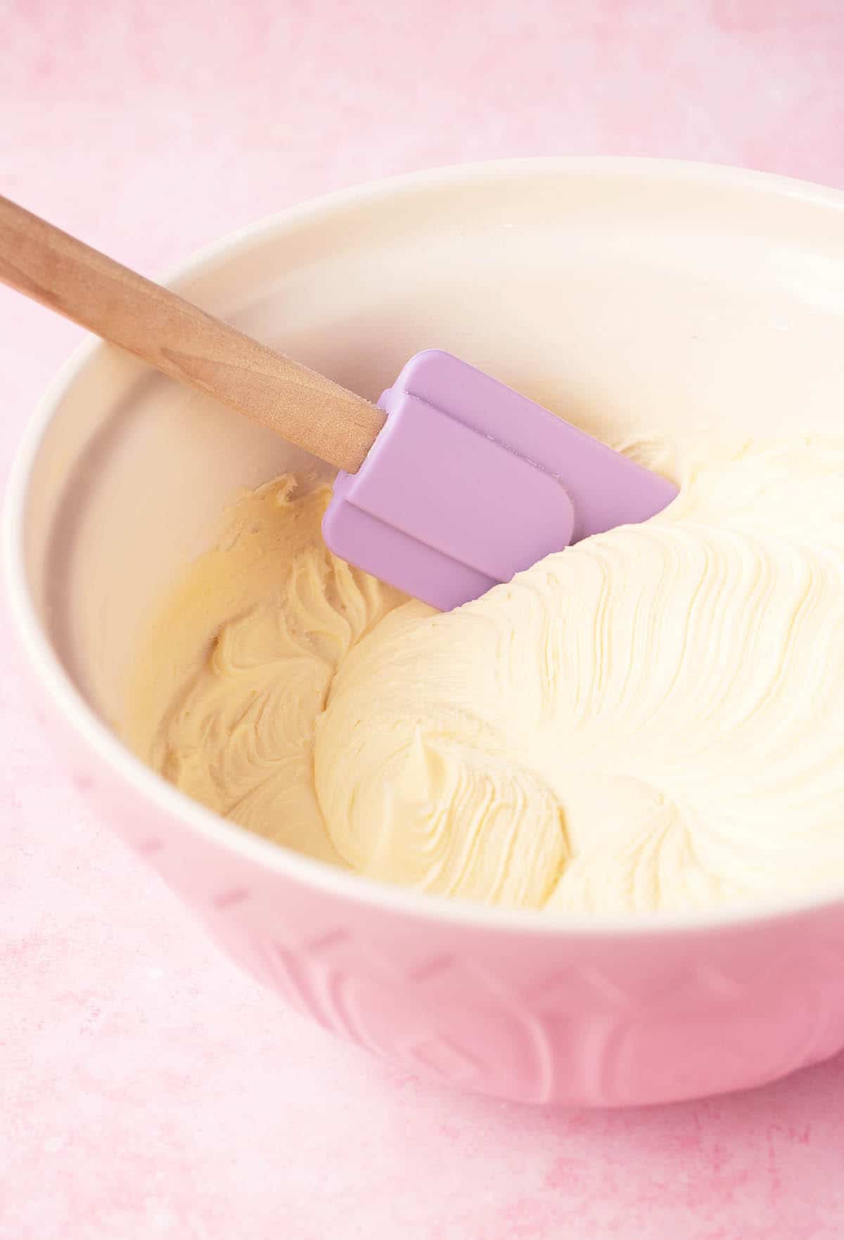 A pink bowl showing beautifully whipped white chocolate frosting. 
