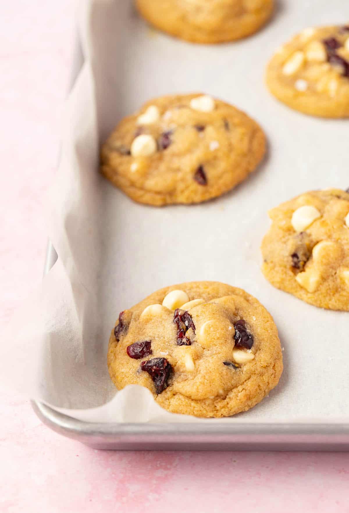 Showing fresh out of the oven white chocolate cranberry cookies sprinkled with sea salt. 