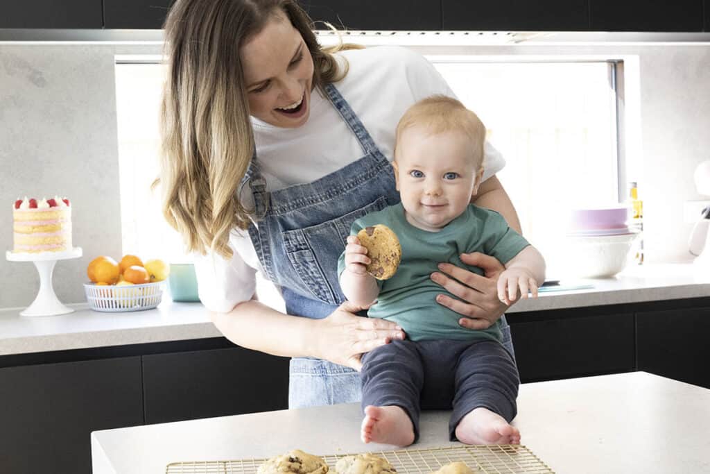 Jessica Holmes and her son eating cookies in the kitchen.