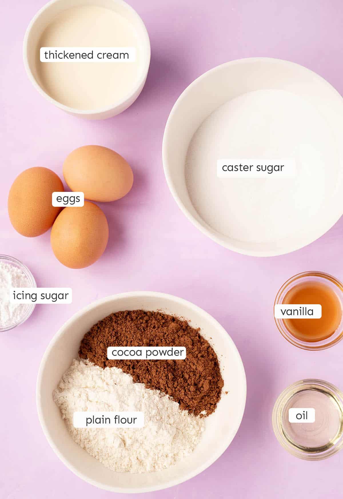 All the ingredients needed to make Chocolate Cake Roll from scratch on a purple backdrop. 