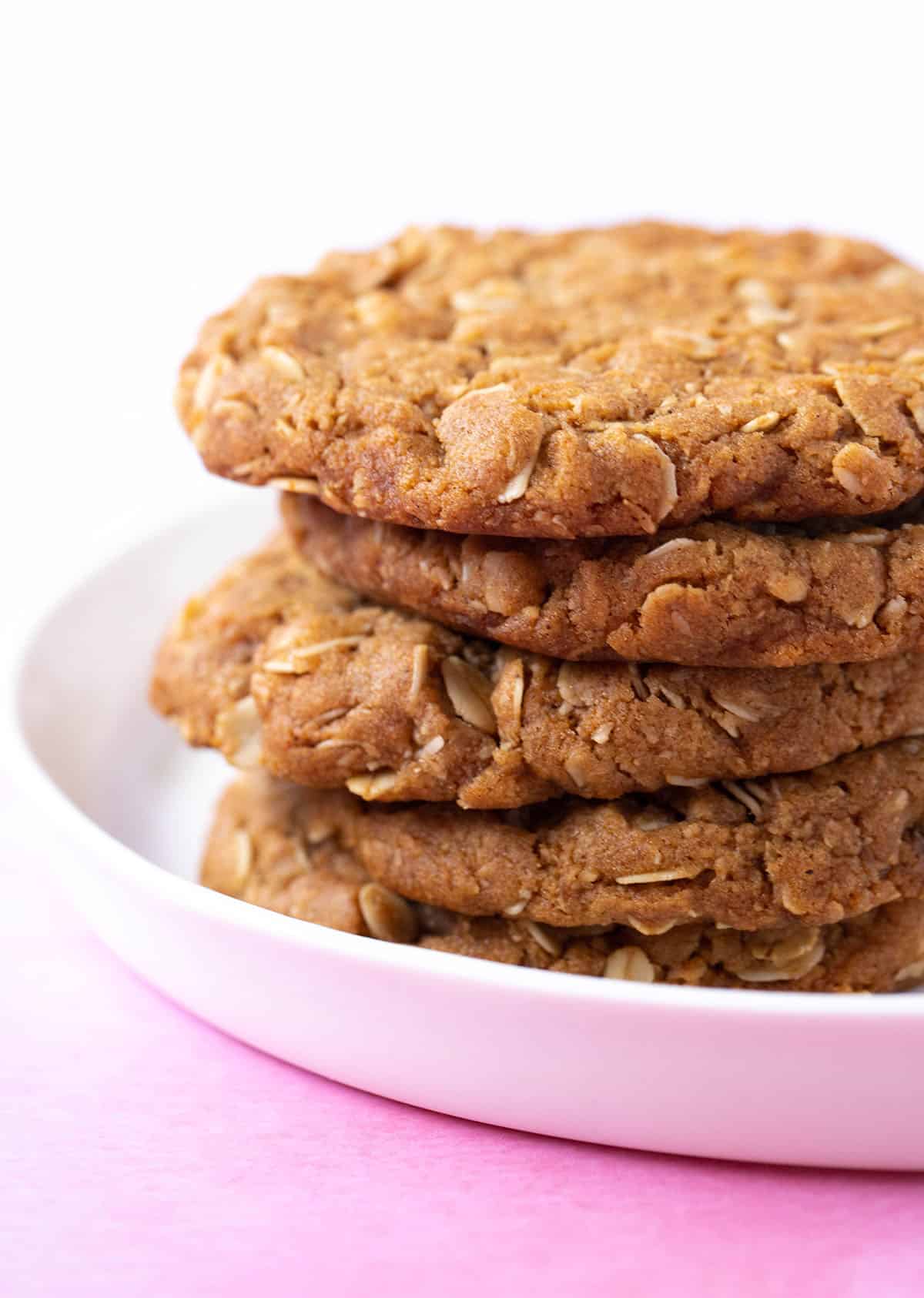 A stack of homemade Anzac Biscuits on a white plate. 