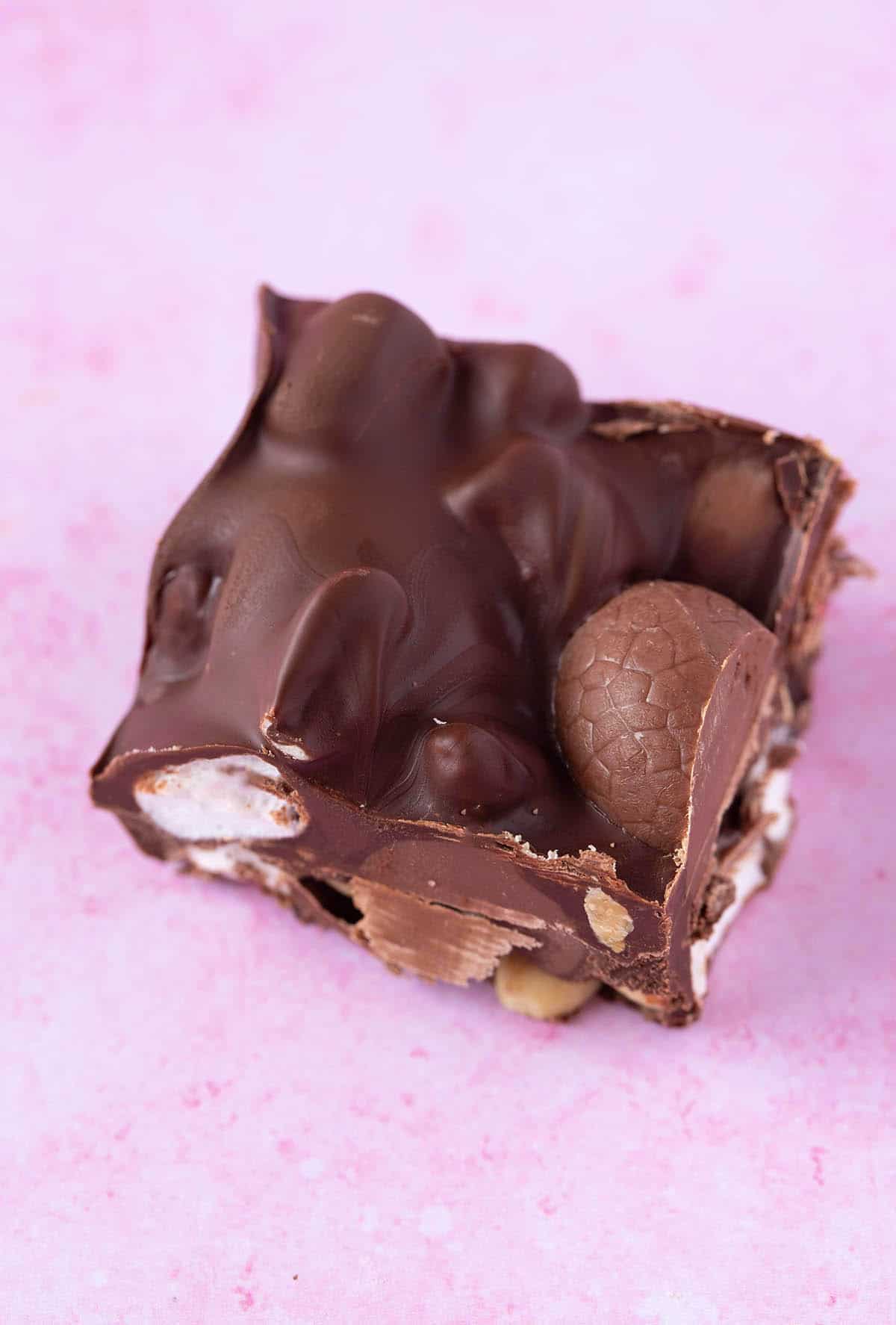 Close up of a delicious piece of easter egg rocky road on a pink backdrop.