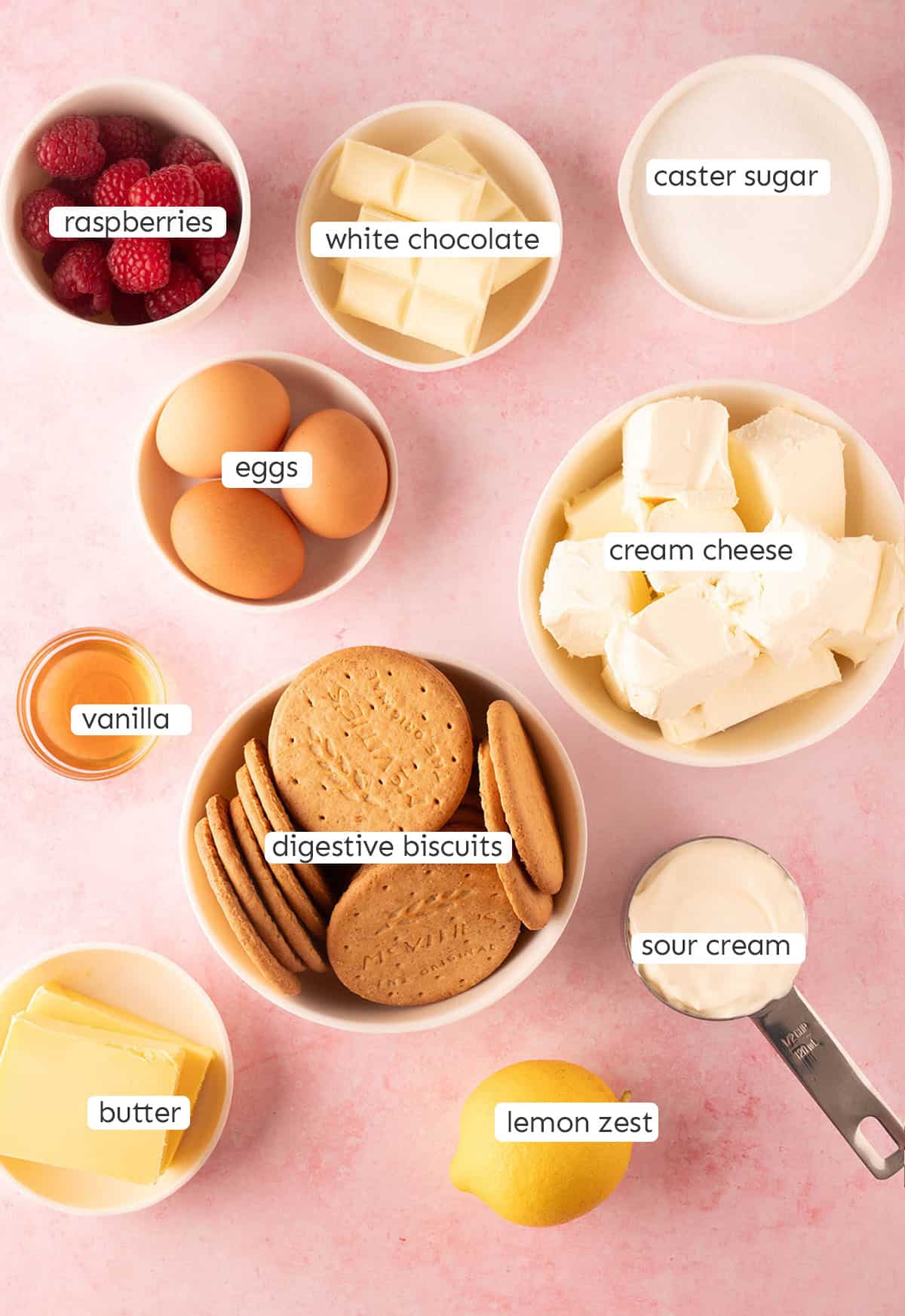 All the ingredients needed to make White Chocolate Cheesecake Bars from scratch on a pink backdrop. 