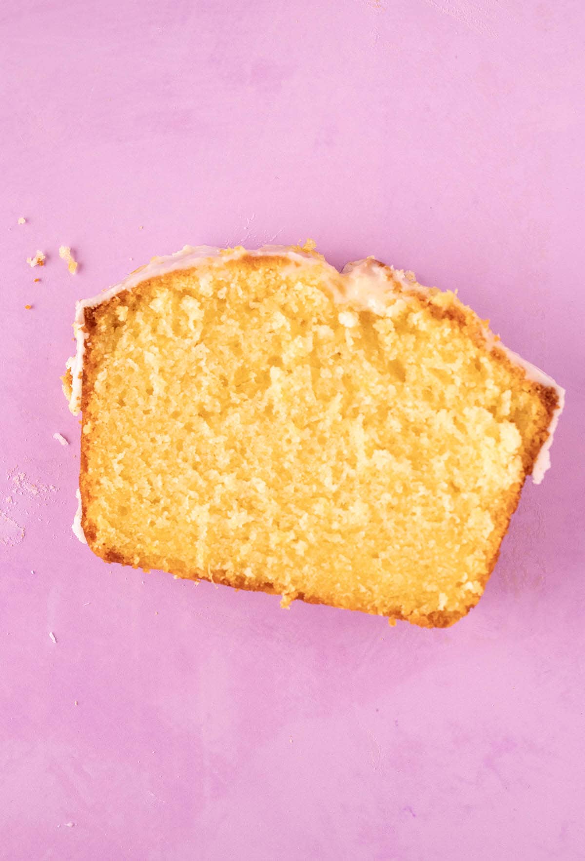 A beautiful piece of Lemon Pound Cake on a purple backdrop. 