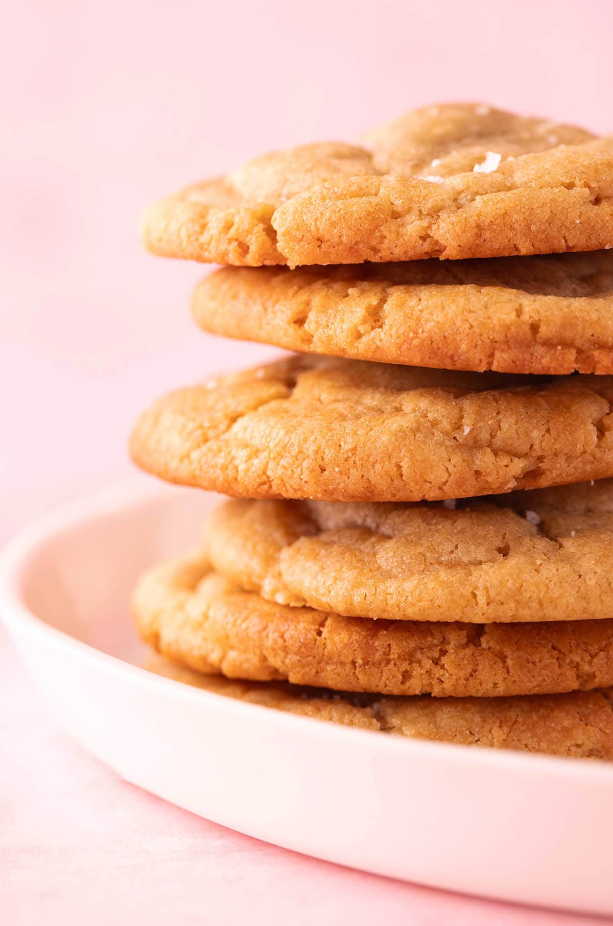 A tall stack of Peanut Butter Miso Cookies on a pink backdrop.