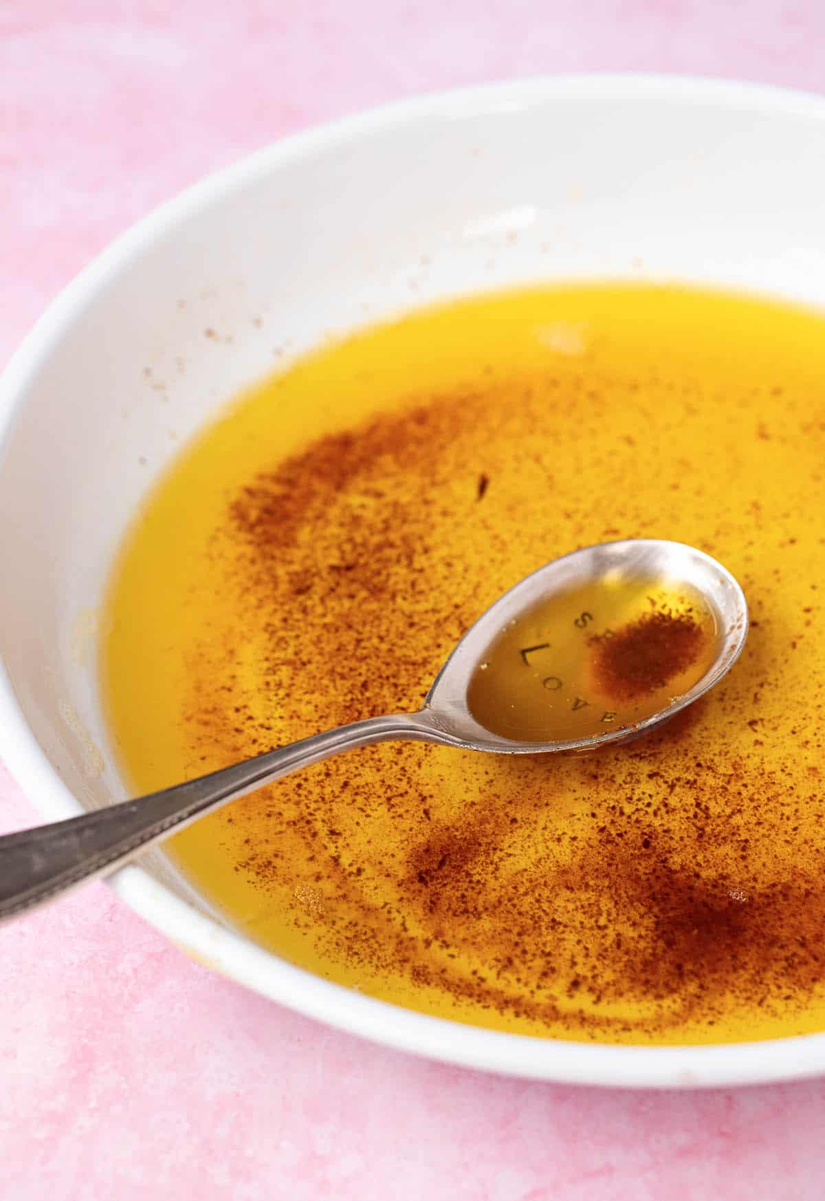 A white plate with brown butter and a decorative serving spoon showing the browned milk solids. 