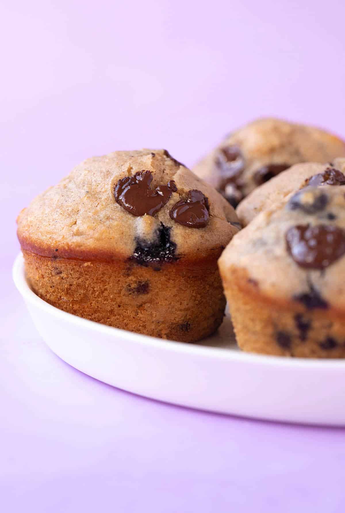A plate of healthy blueberry muffins on a purple backdrop.