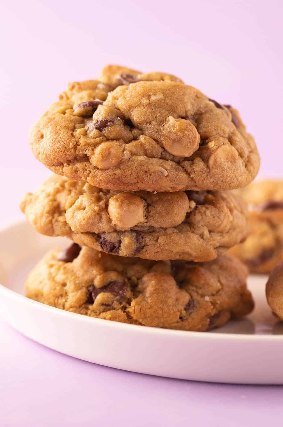 A tall stack of caramel coconut cookies on a purple backdrop.