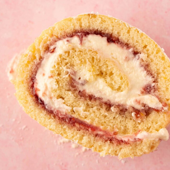 Perfect slice of vanilla swiss cake roll on a pink background.