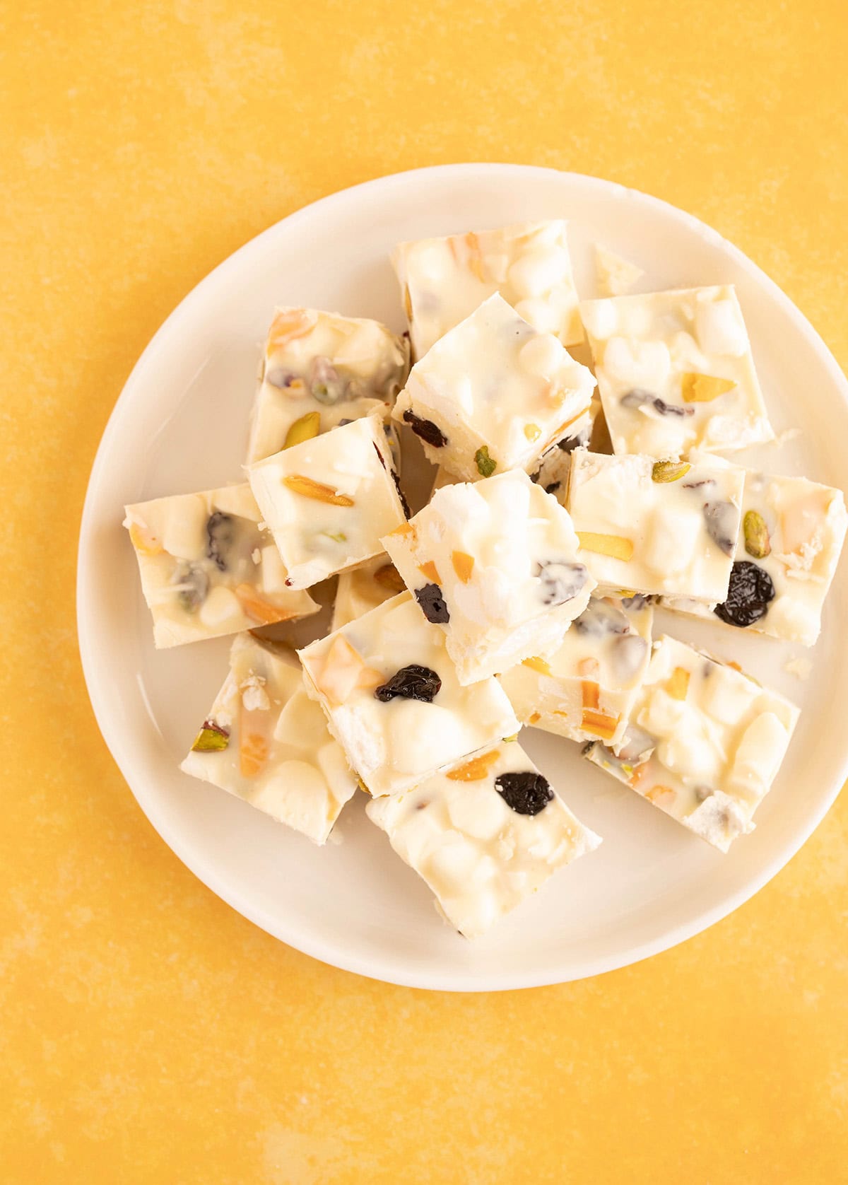 Top view of a plate of Pavlova Rocky Road on a yellow background.