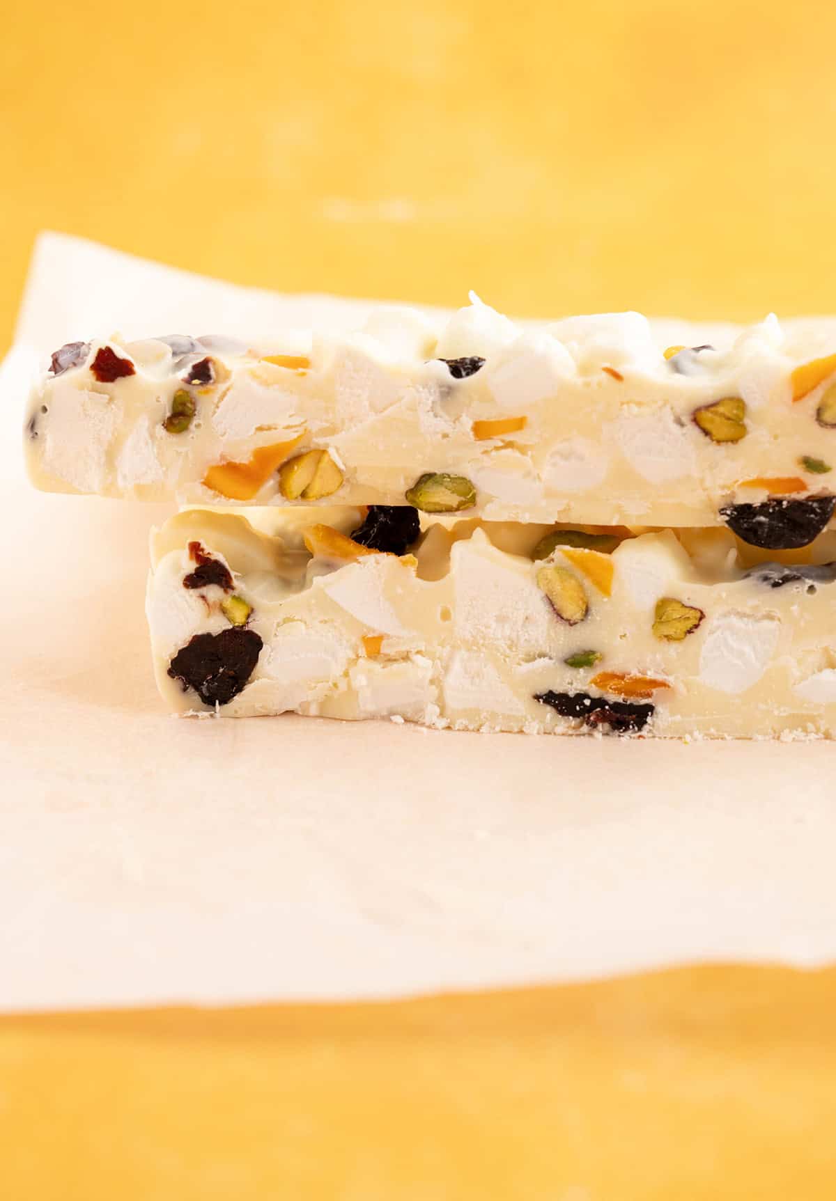 A slice of homemade Pavlova Rocky Road on a yellow backdrop.