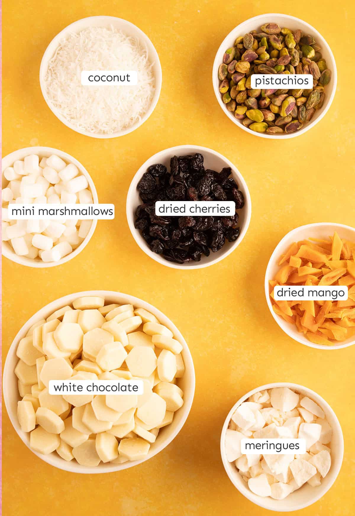 All the ingredients needed to make Pavlova Rocky Road from scratch laid out on a yellow backdrop.