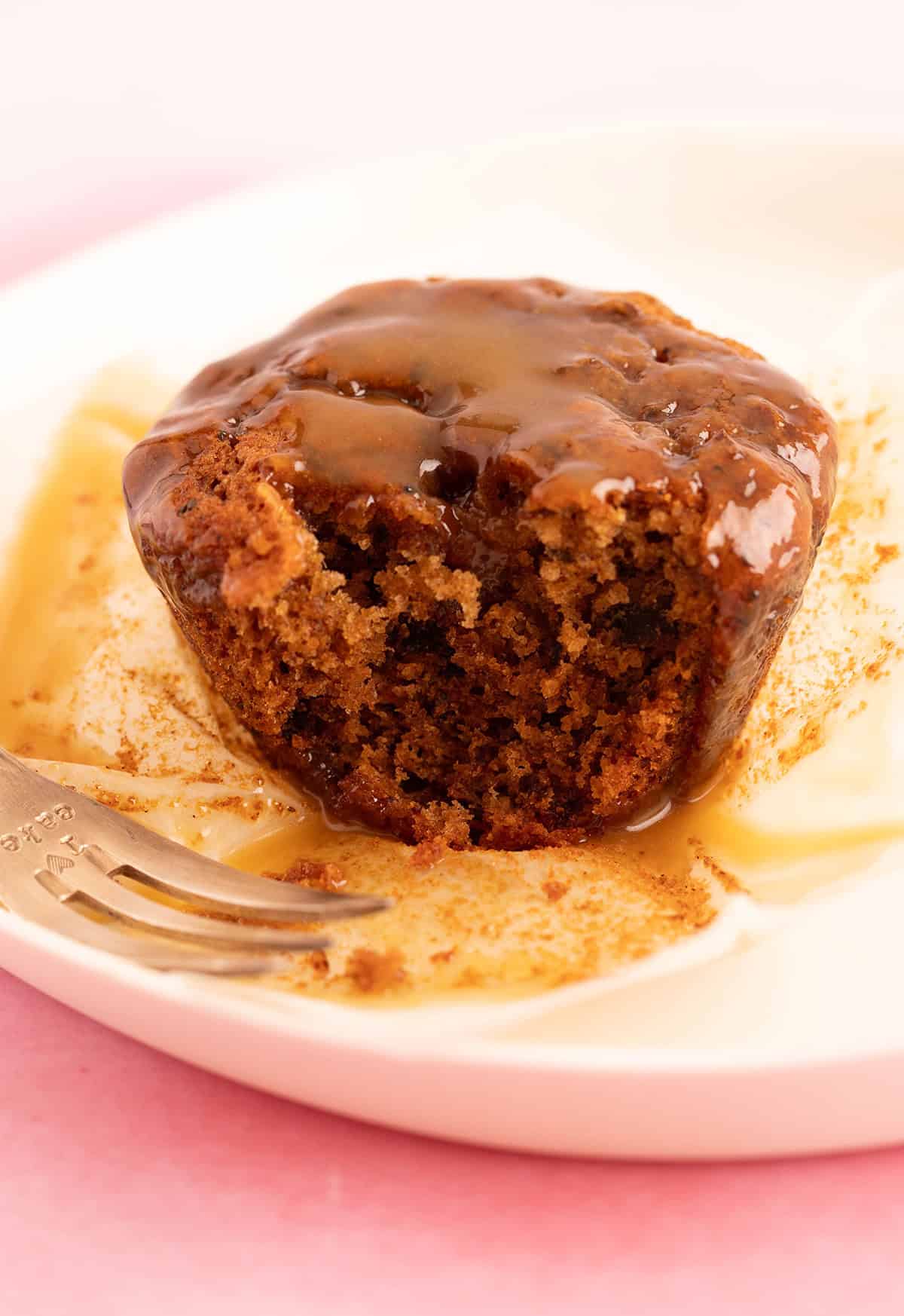 A sticky date muffin with a bite taken out of it.