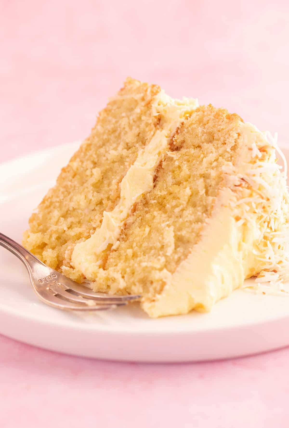 A big slice of Lemon Coconut Cake on a white plate.