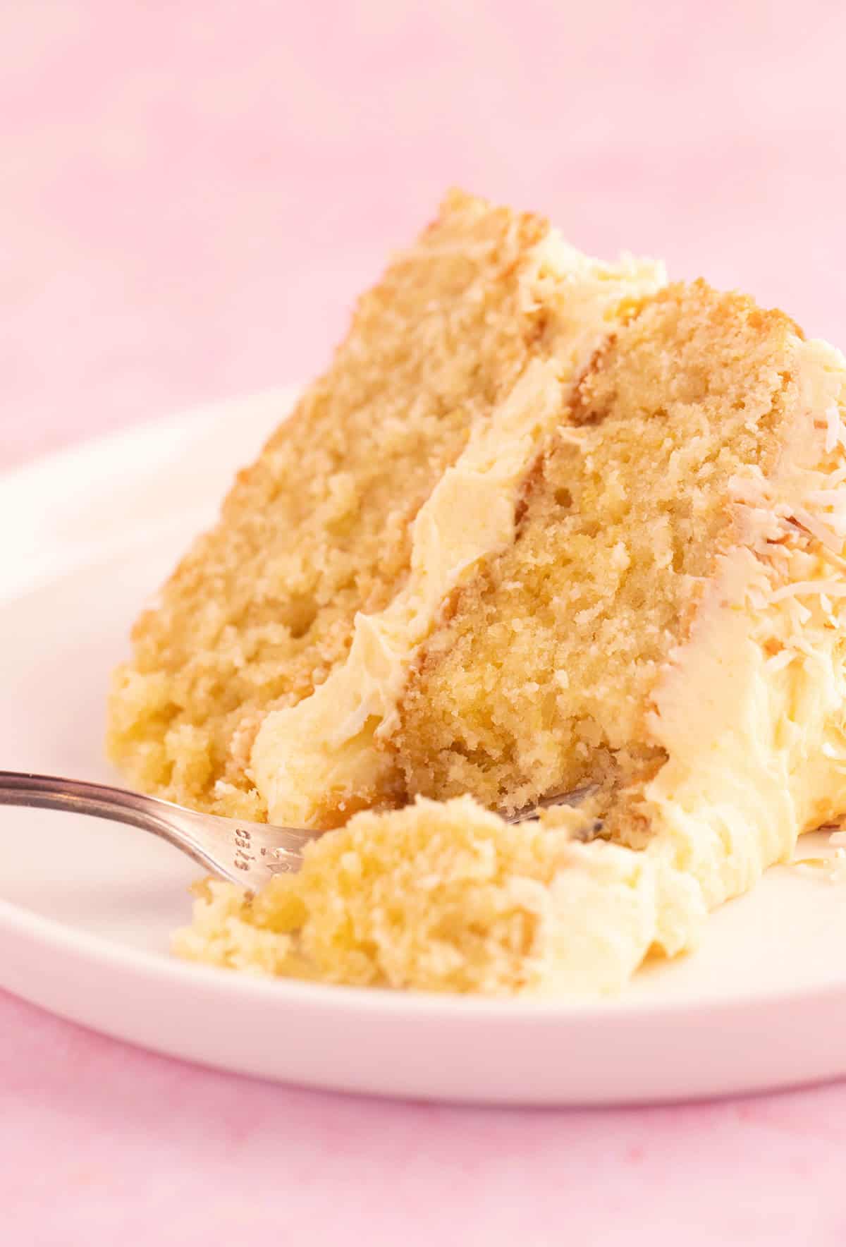 A big slice of Lemon Coconut Cake showing the fluffy texture inside. 