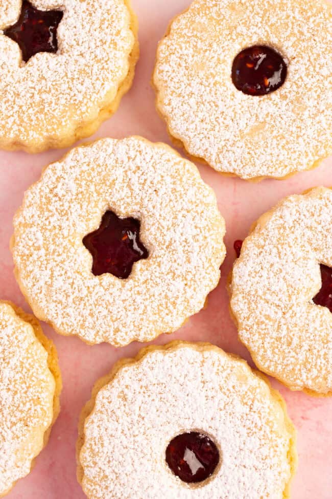Beautiful Linzer Cookies on a pink backdrop.