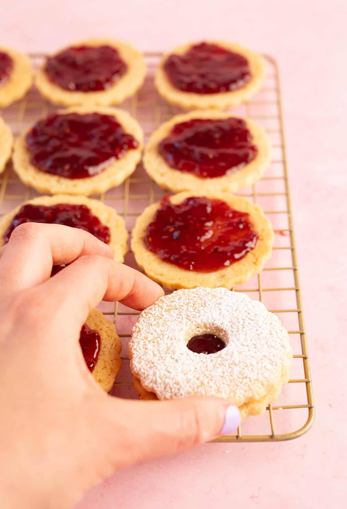 Placing the top Linzer cookie on top of the jammy bottom cookie.