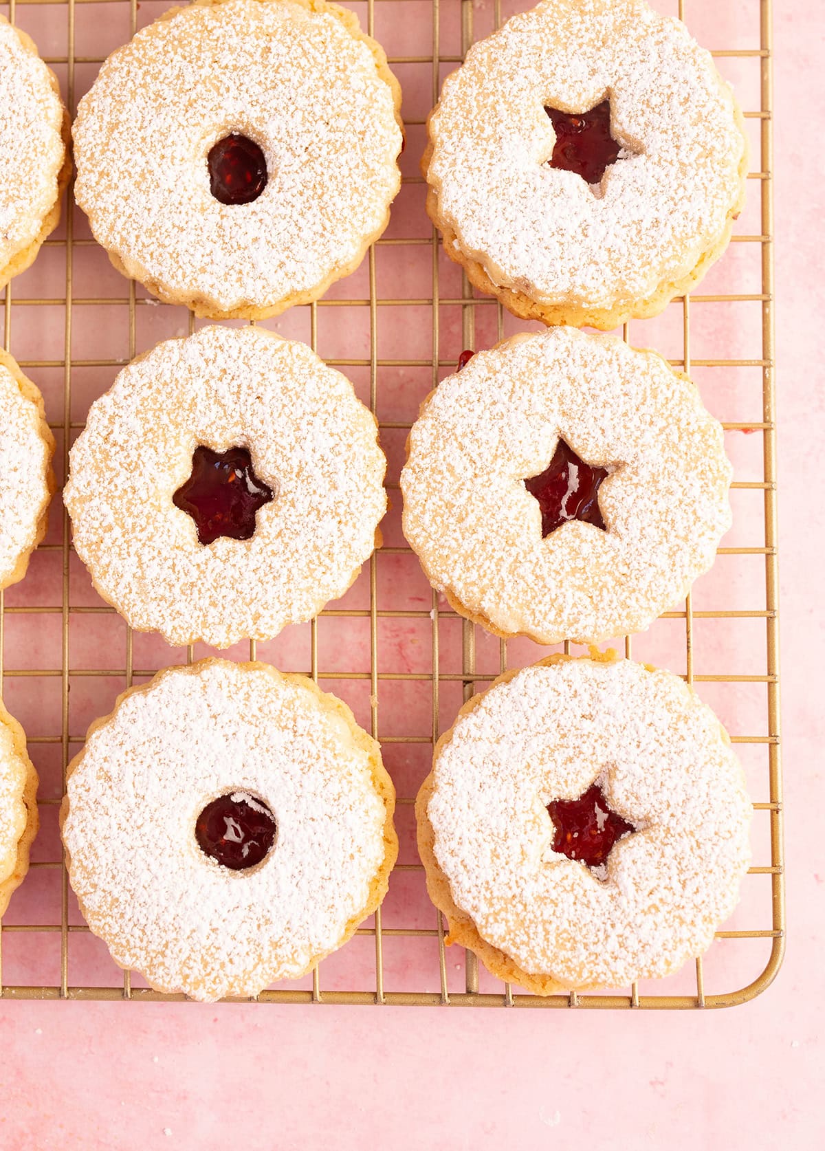Beautifully decorated raspberry Linzer Cookies on a gold baking rack.
