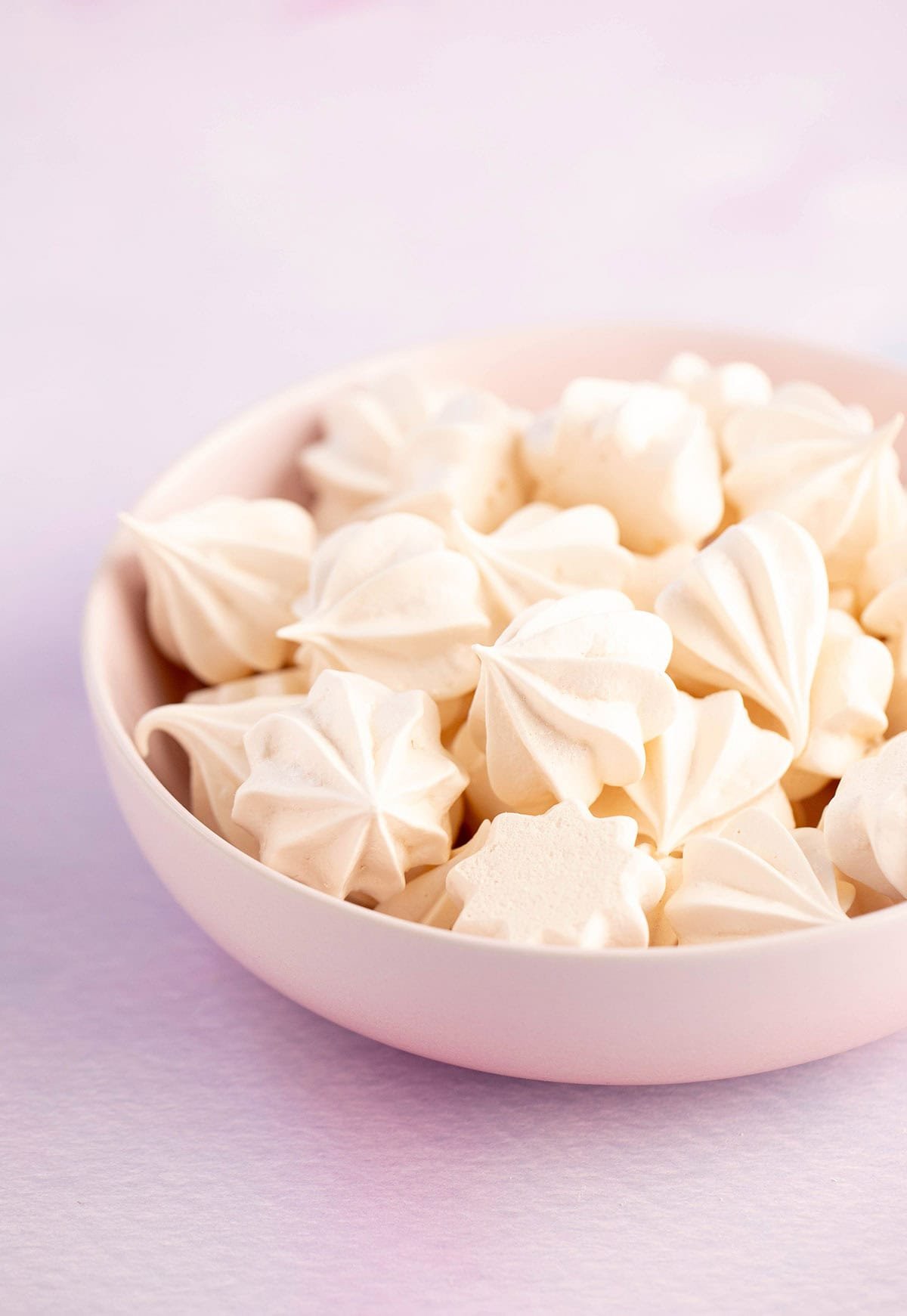A pink bowl filled with homemade meringue cookies.