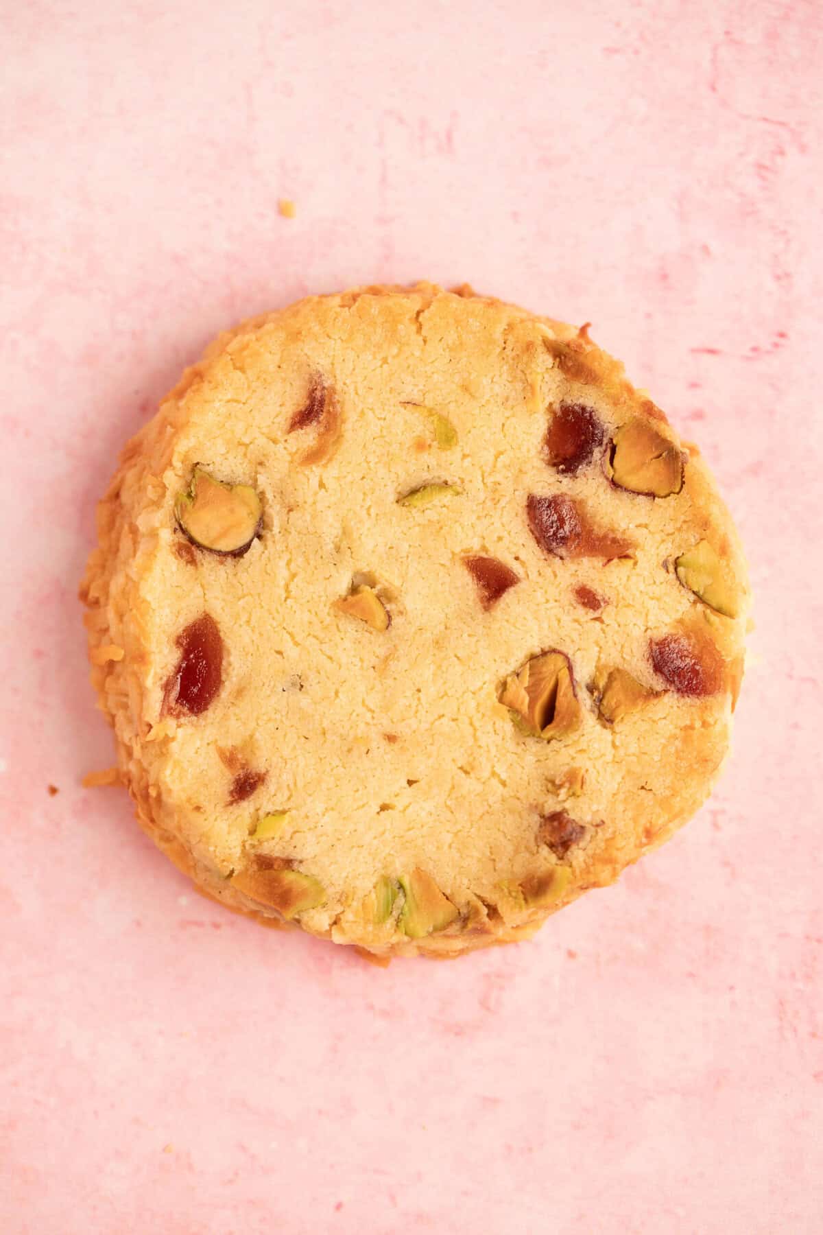 Close up of a single Slice and Bake Cookie filled with cherries and pistachios. 